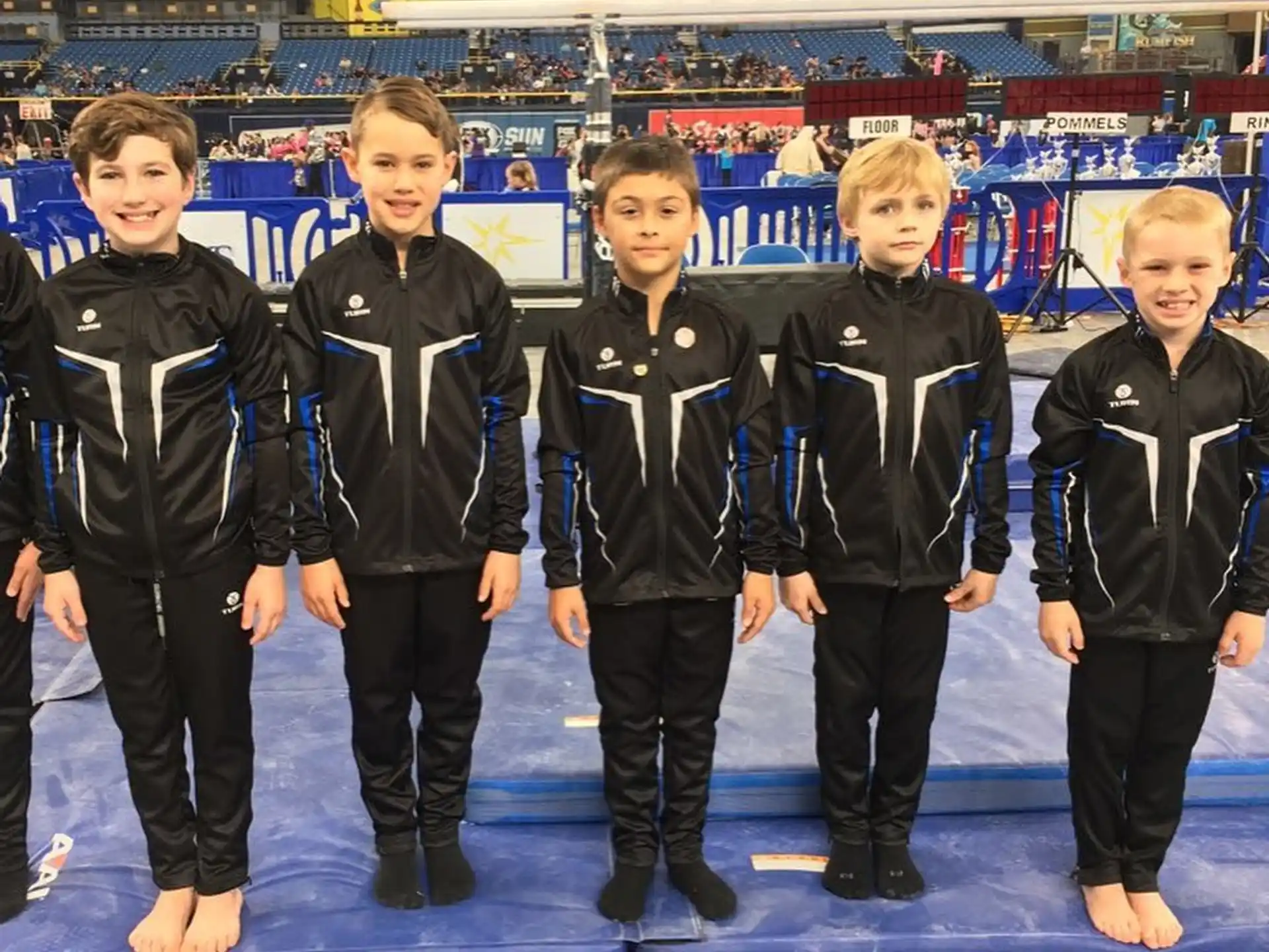 a group of boys in black and white uniforms standing on a blue mat