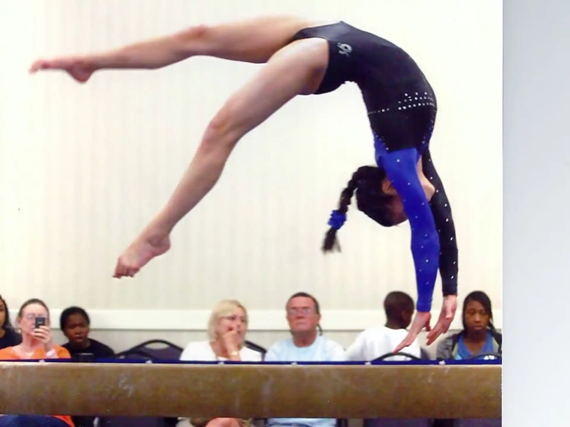 a person doing a handstand on a wooden railing in front of a crowd