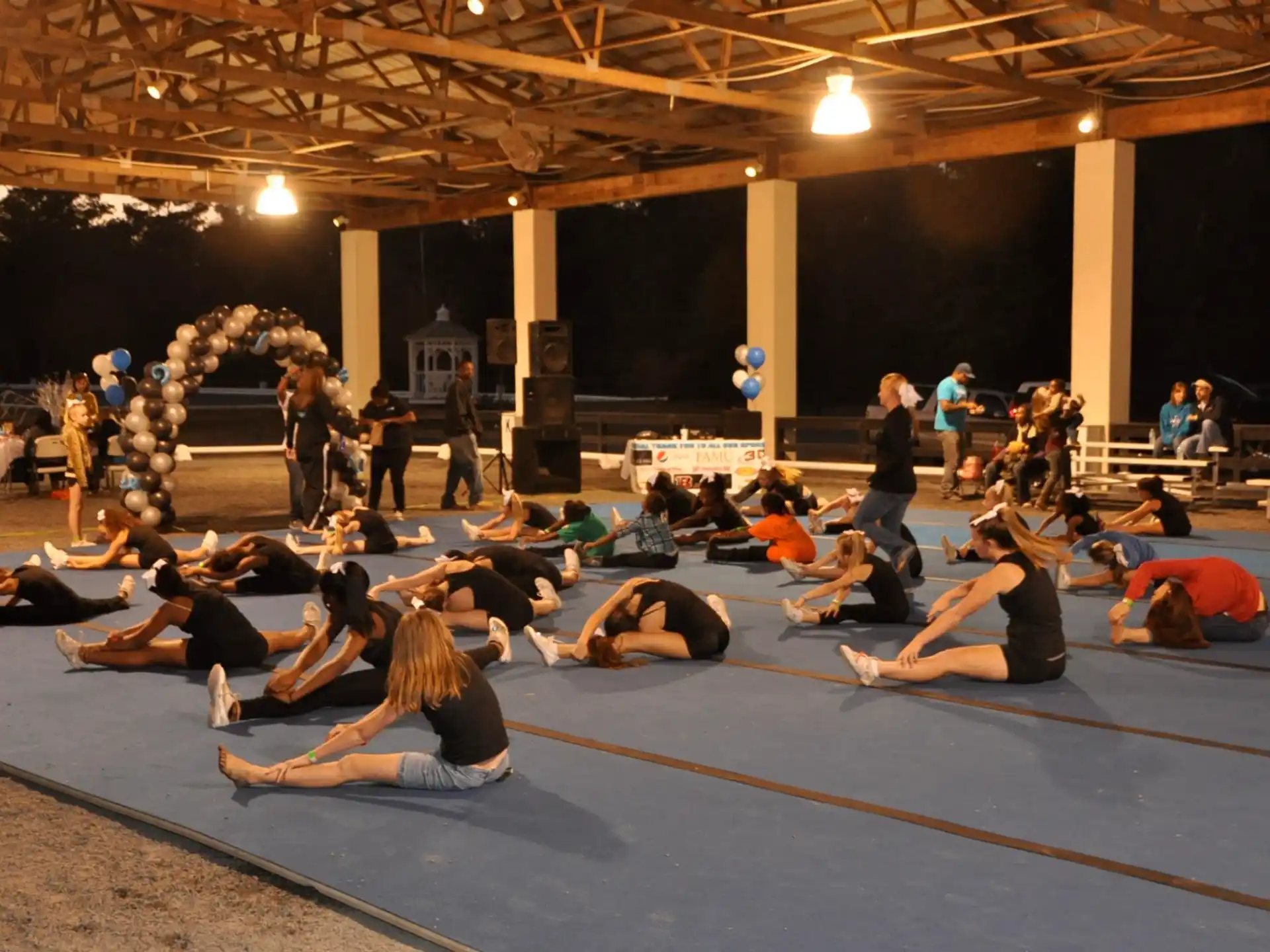 a group of people exercising in a room with a stage and a crowd