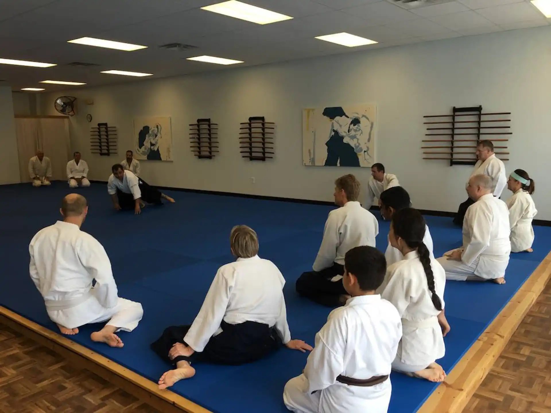 a group of people in white robes sitting on a mat in a room