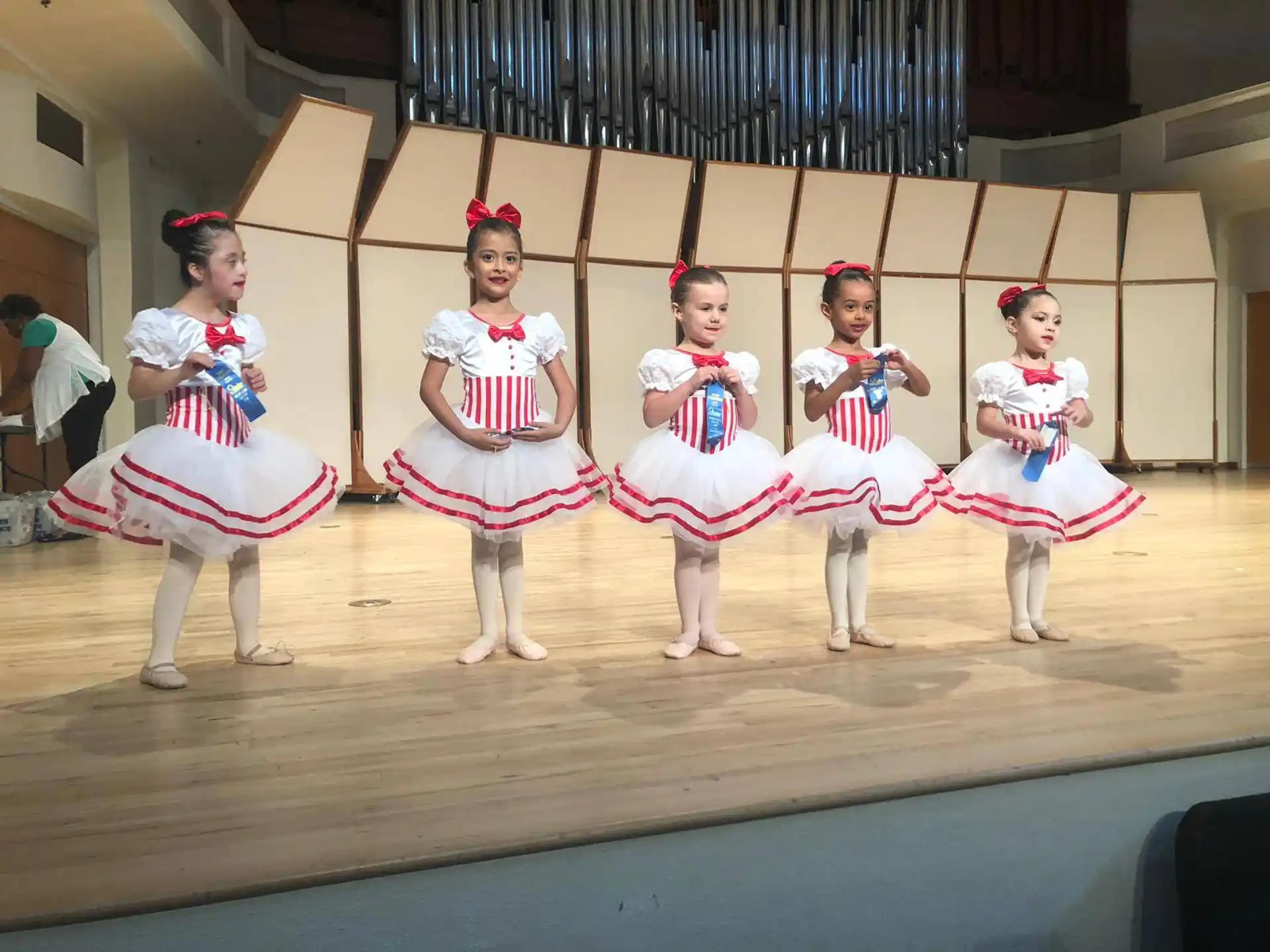 a group of girls in white dresses and red and white sashes