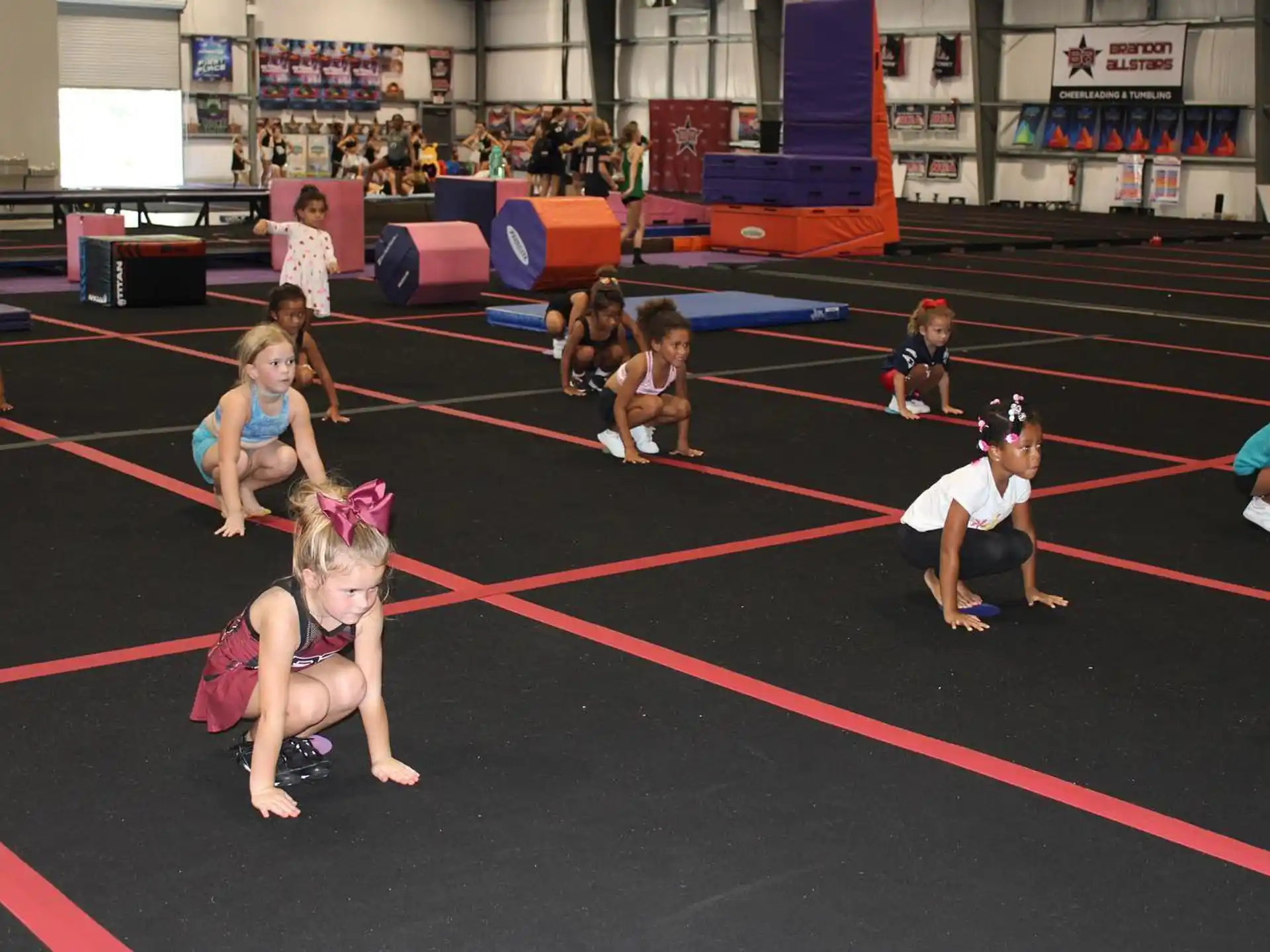 a group of children sitting on the floor in a gym