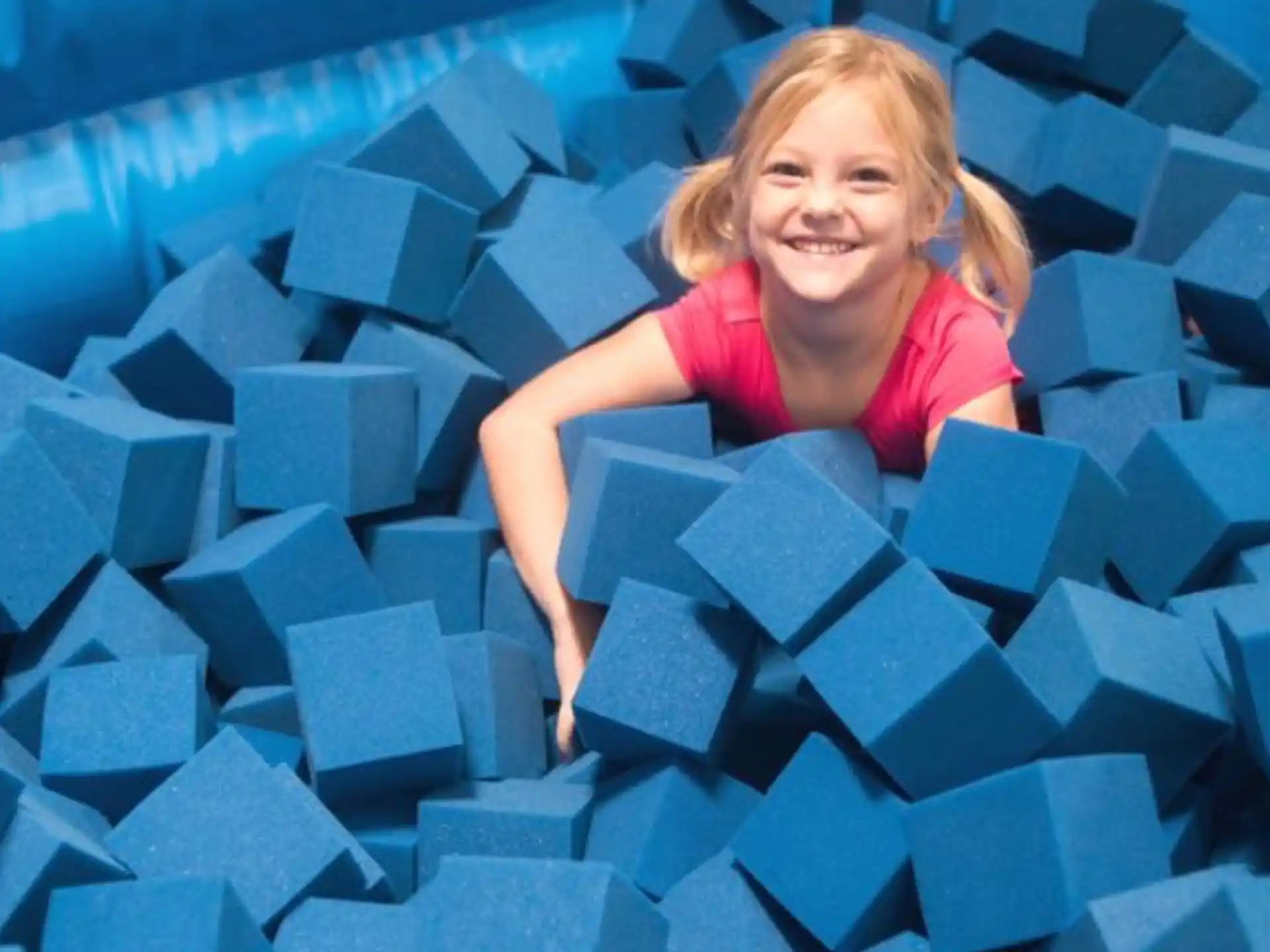 a girl smiling with a pile of blue blocks