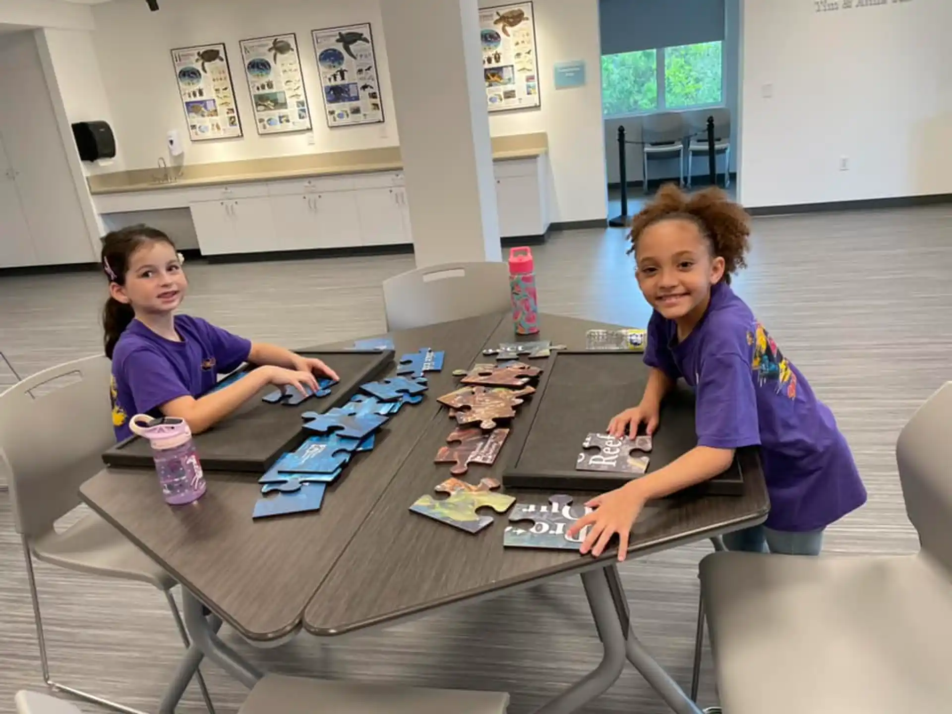 a few young girls sitting at a table with a game