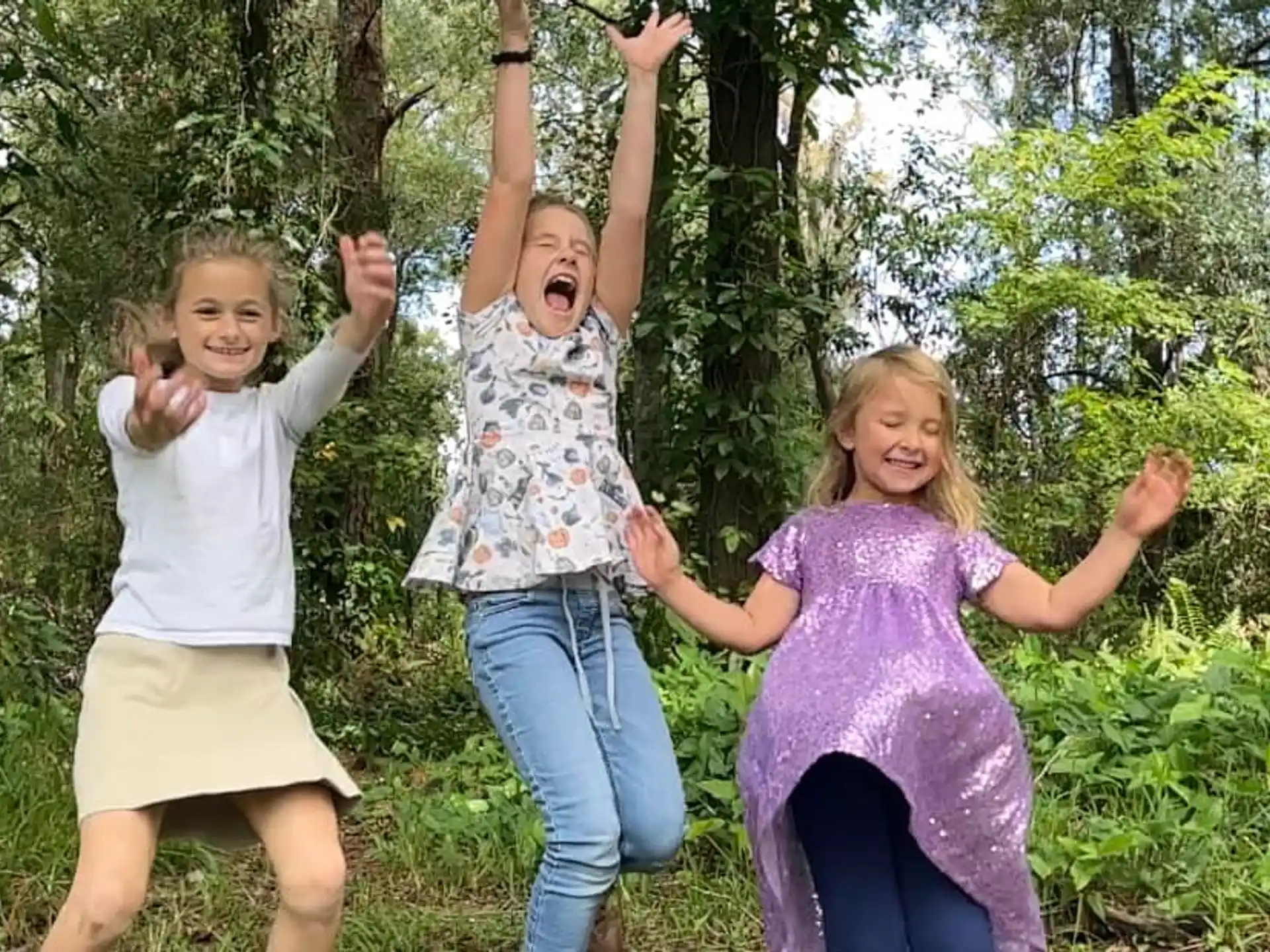 a group of girls jumping in the air in the woods