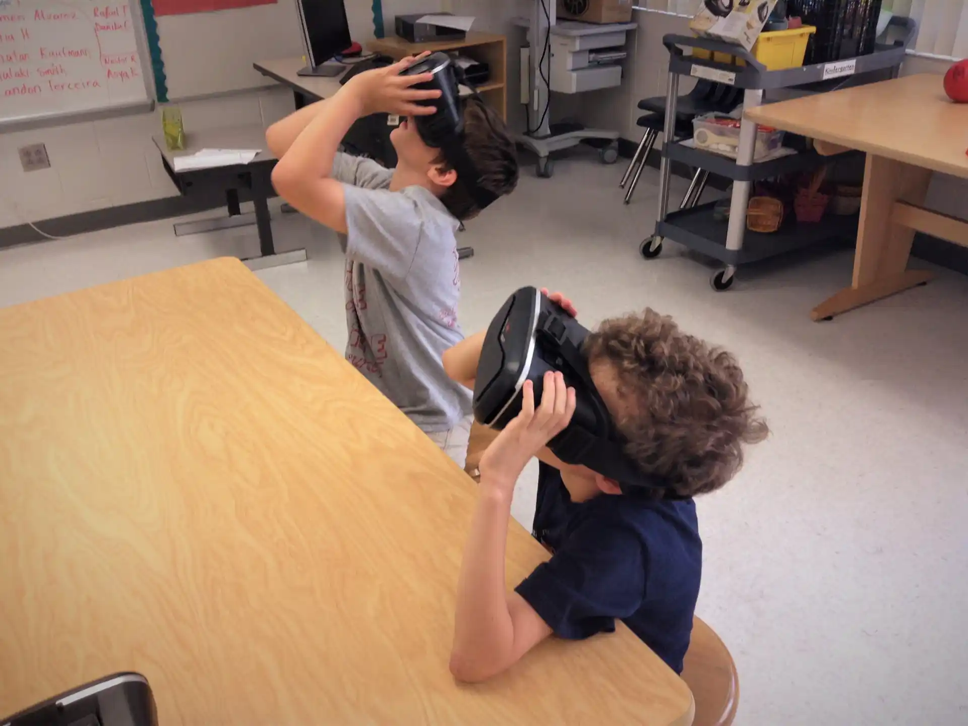 a couple of boys sitting at a table with a backpack on