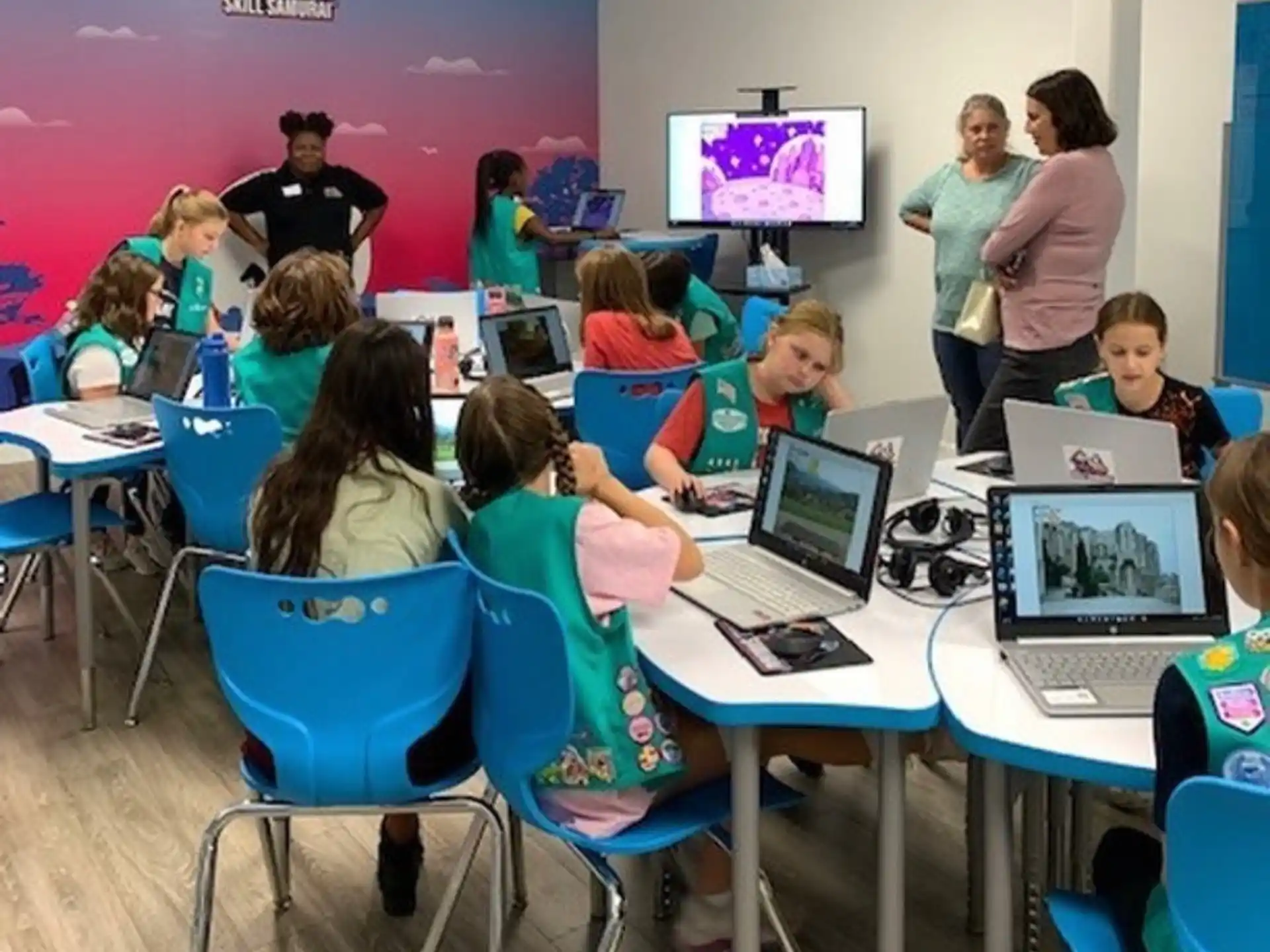 a group of children sitting at desks with laptops