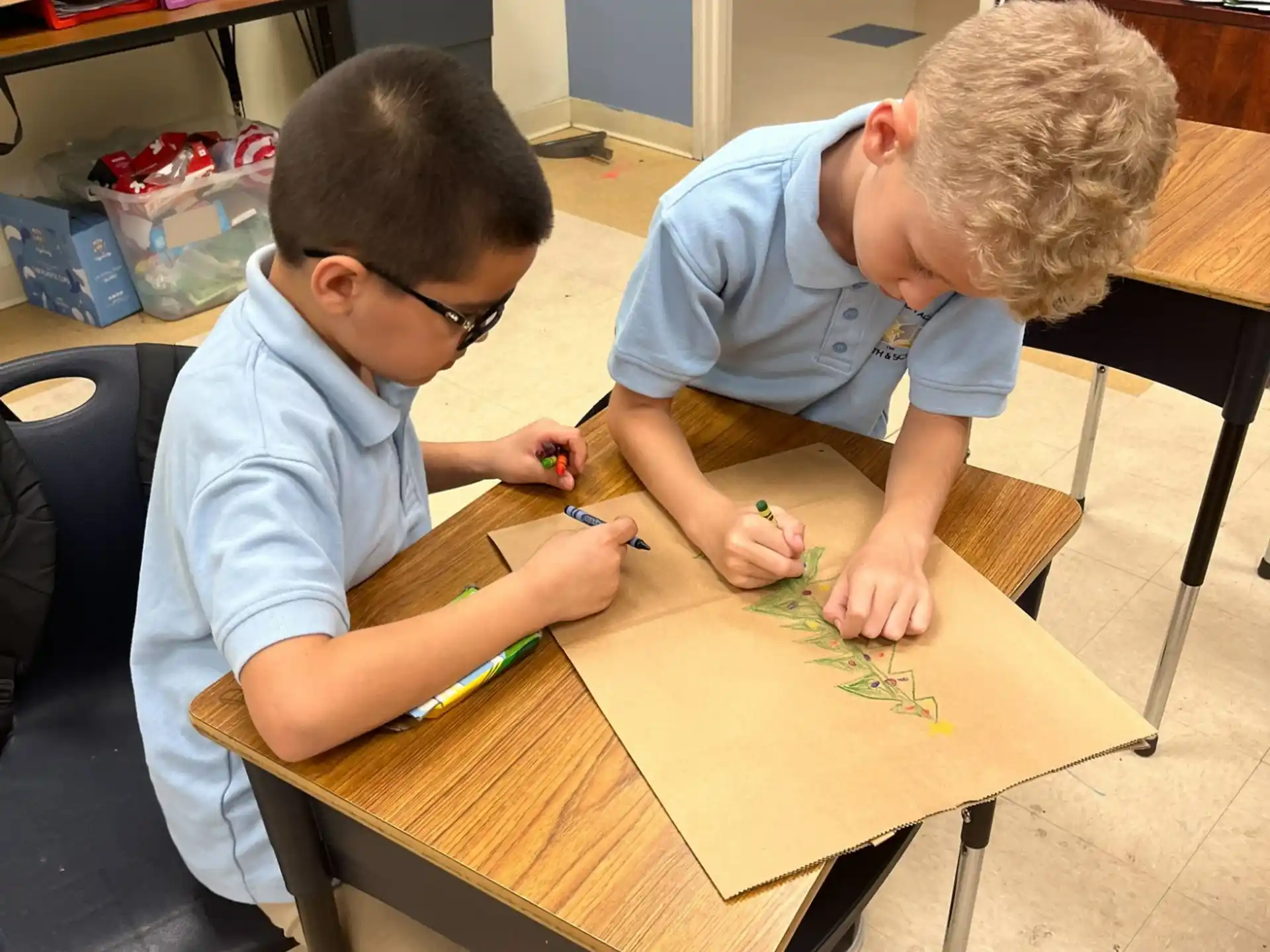 a couple of boys sitting at a table looking at a piece of paper