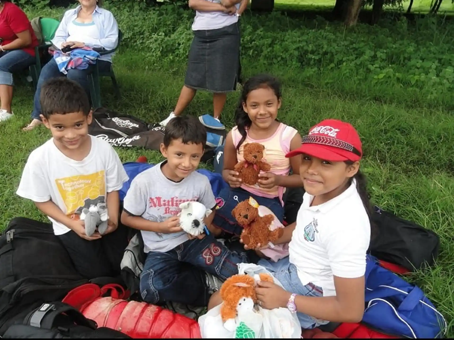 a group of children sitting on a blanket in a grassy area