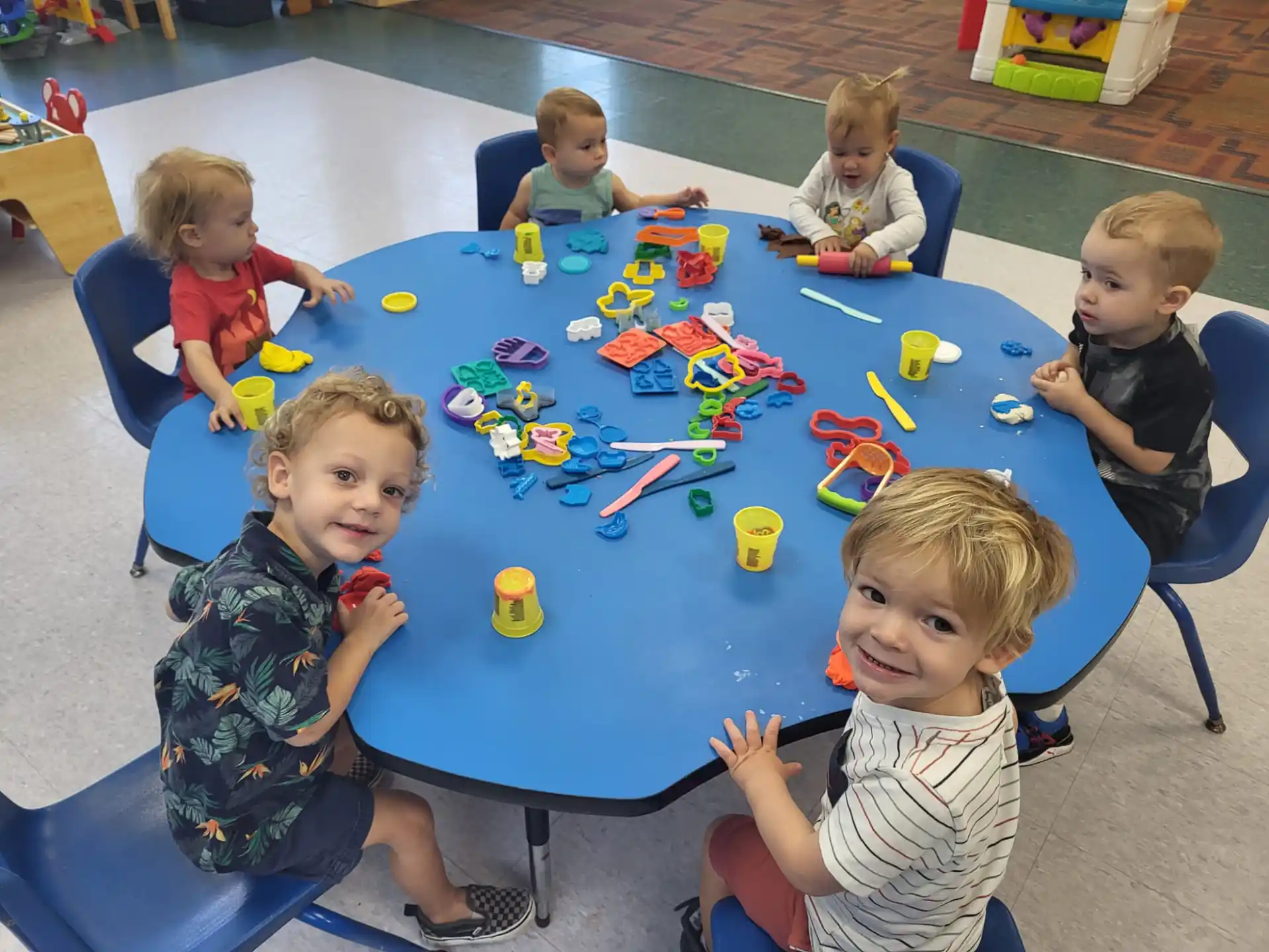 a group of children sitting around a table with toys on it