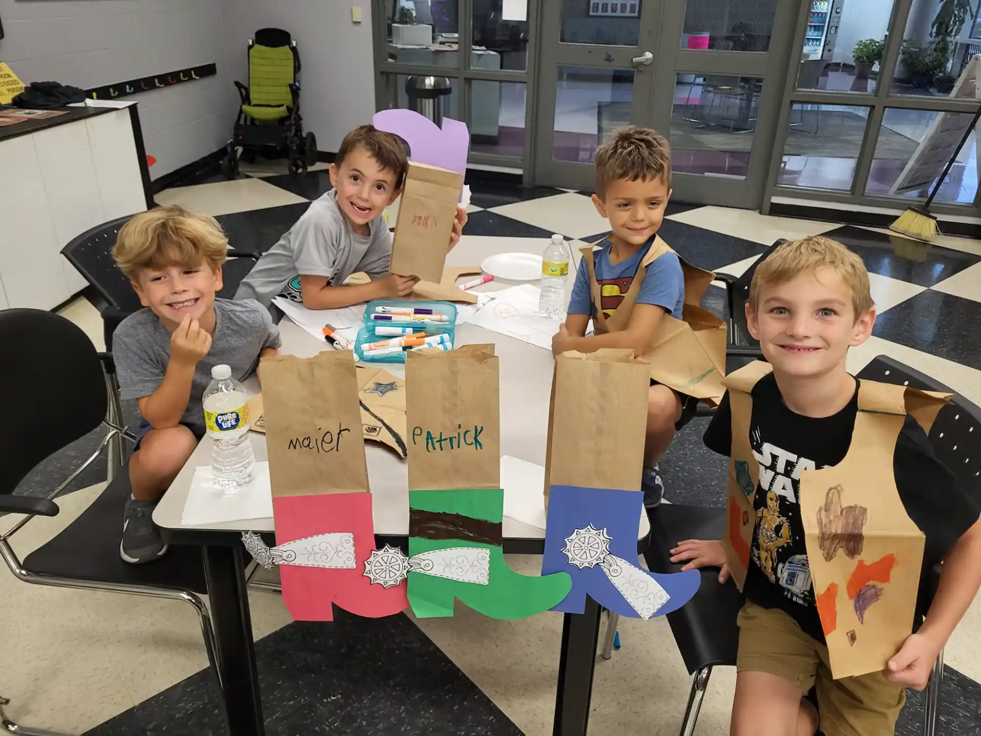 a group of boys sitting at a table with boxes and a sign