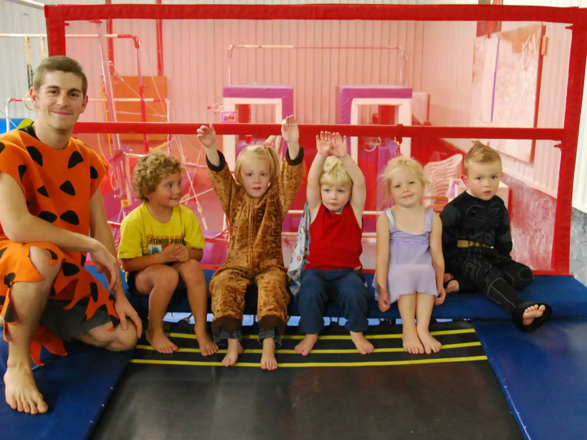 a group of children sitting on a mat posing for the camera