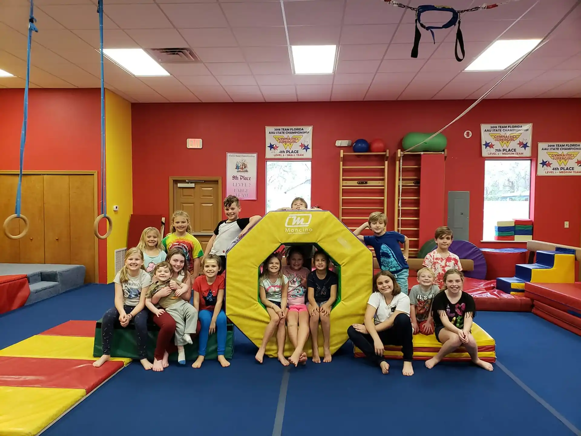 a group of people posing for a photo in a room with a large yellow and blue slide