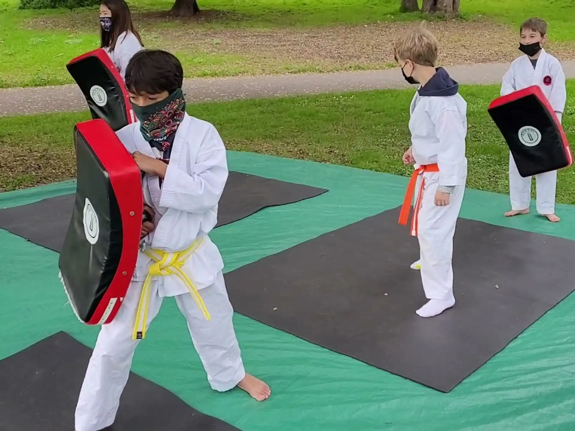 a group of people in white karate uniforms on a green mat