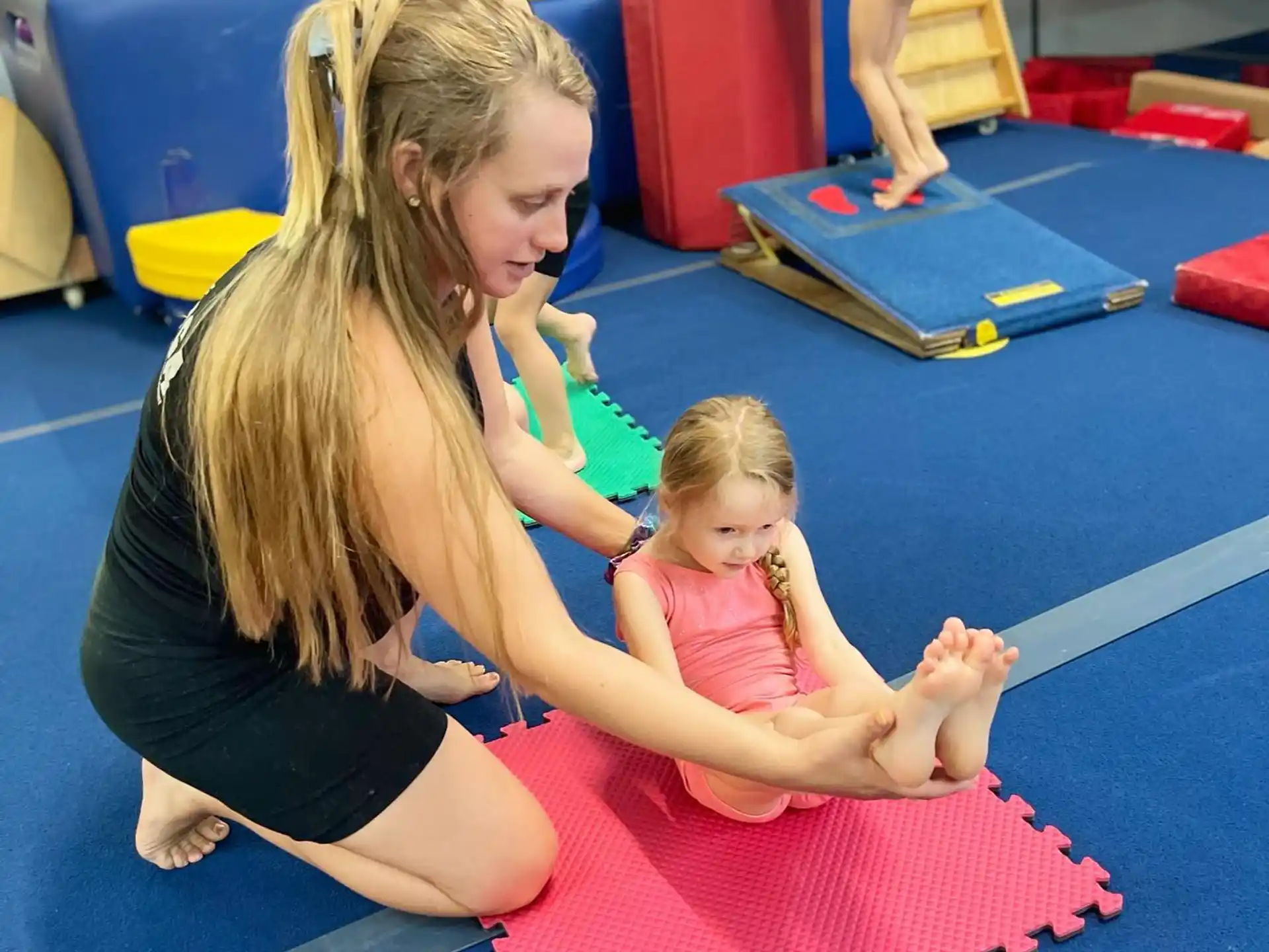a person and a couple of children on a mat in a gym