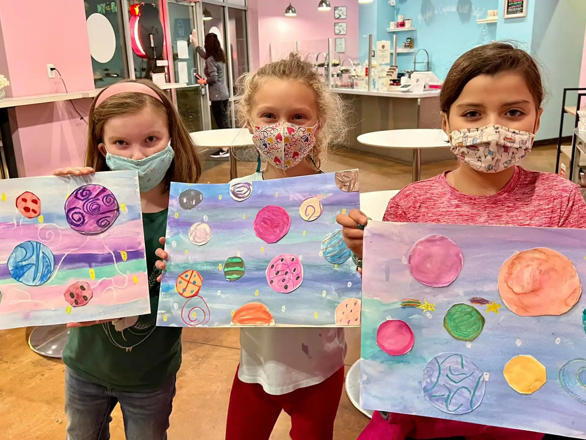a group of children holding up paper crafts