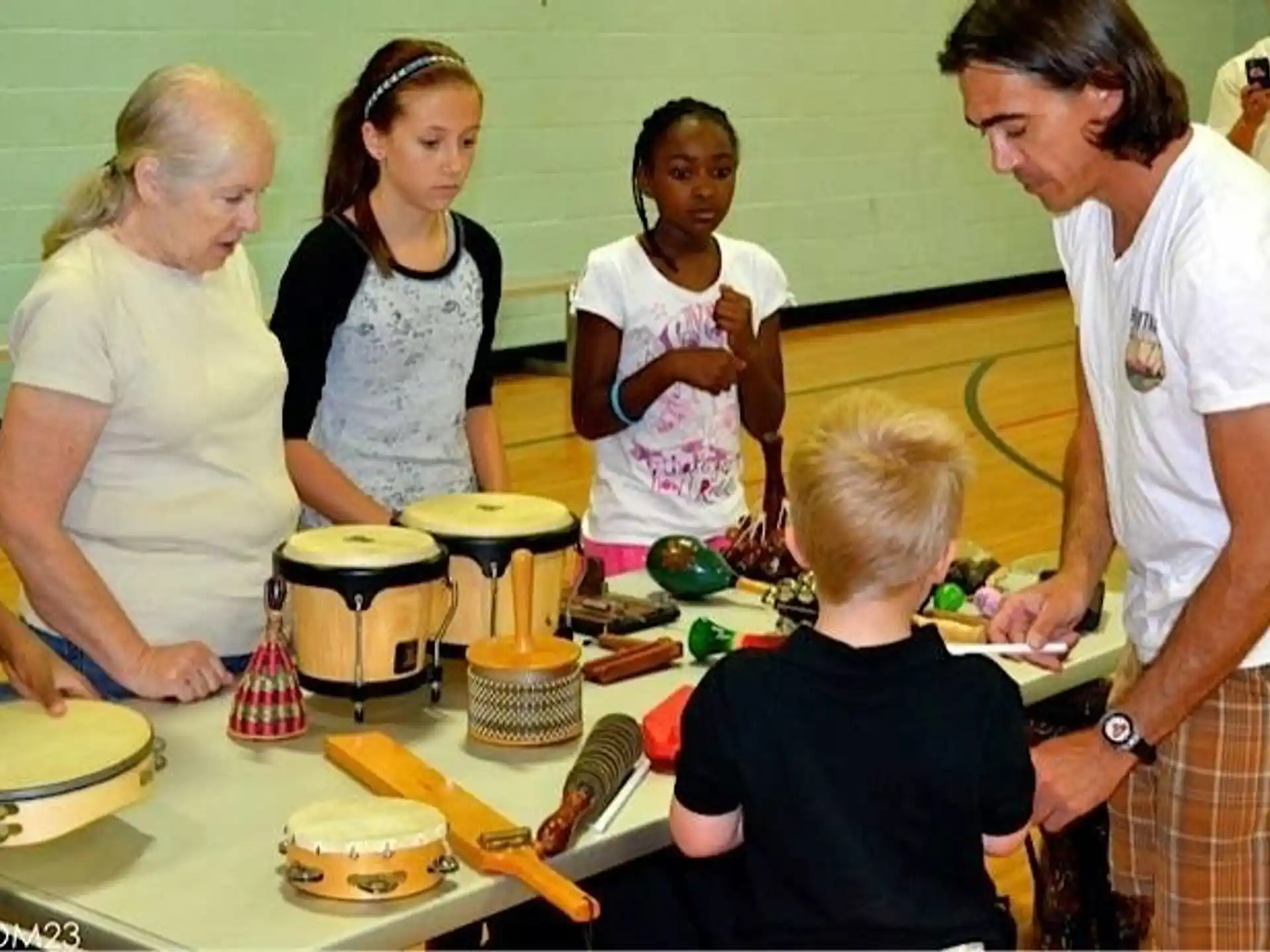 a group of people gather around a table with cakes