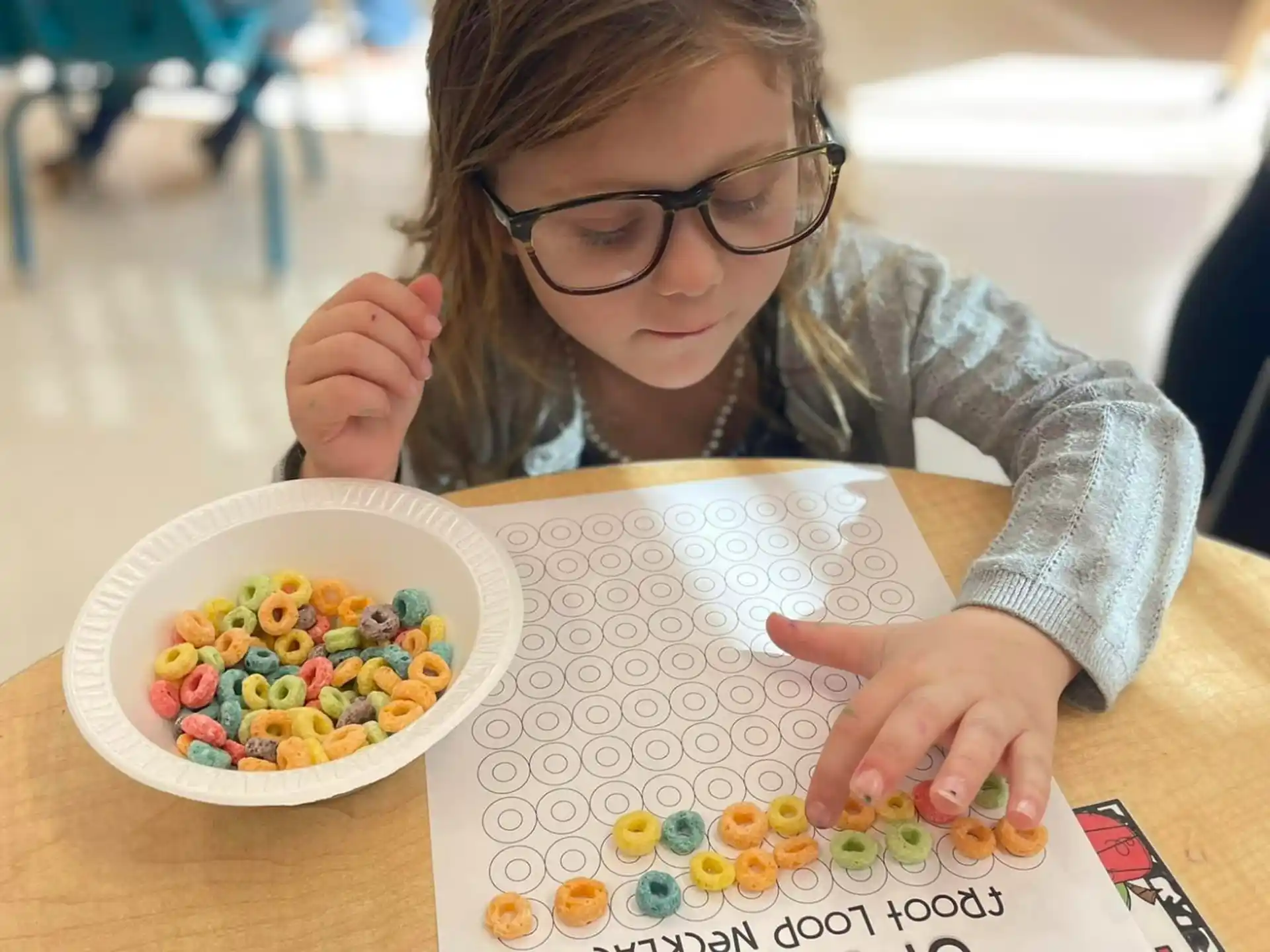 a girl sitting at a table with a bowl of cereal and a bowl of cereal