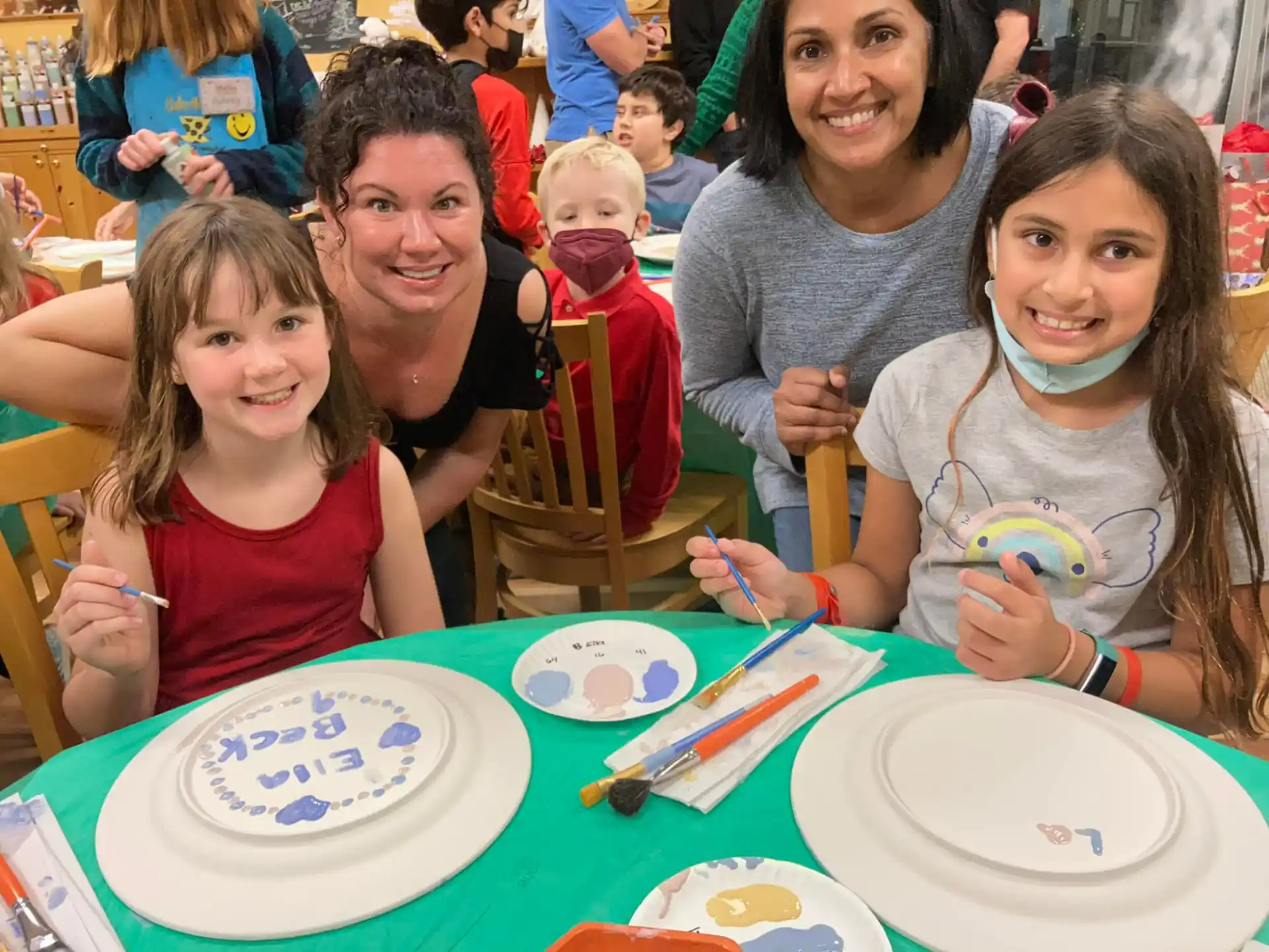 a group of people sitting at a table with plates and cups