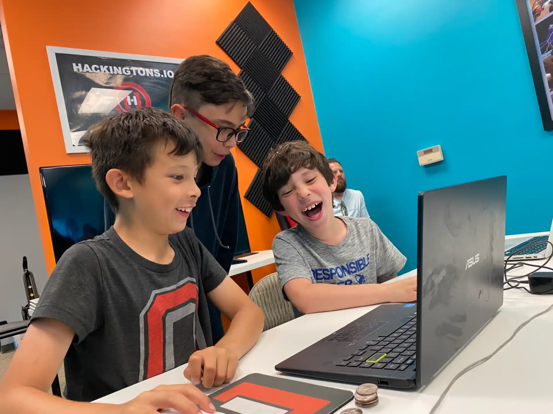 a group of boys sitting at a table with a laptop