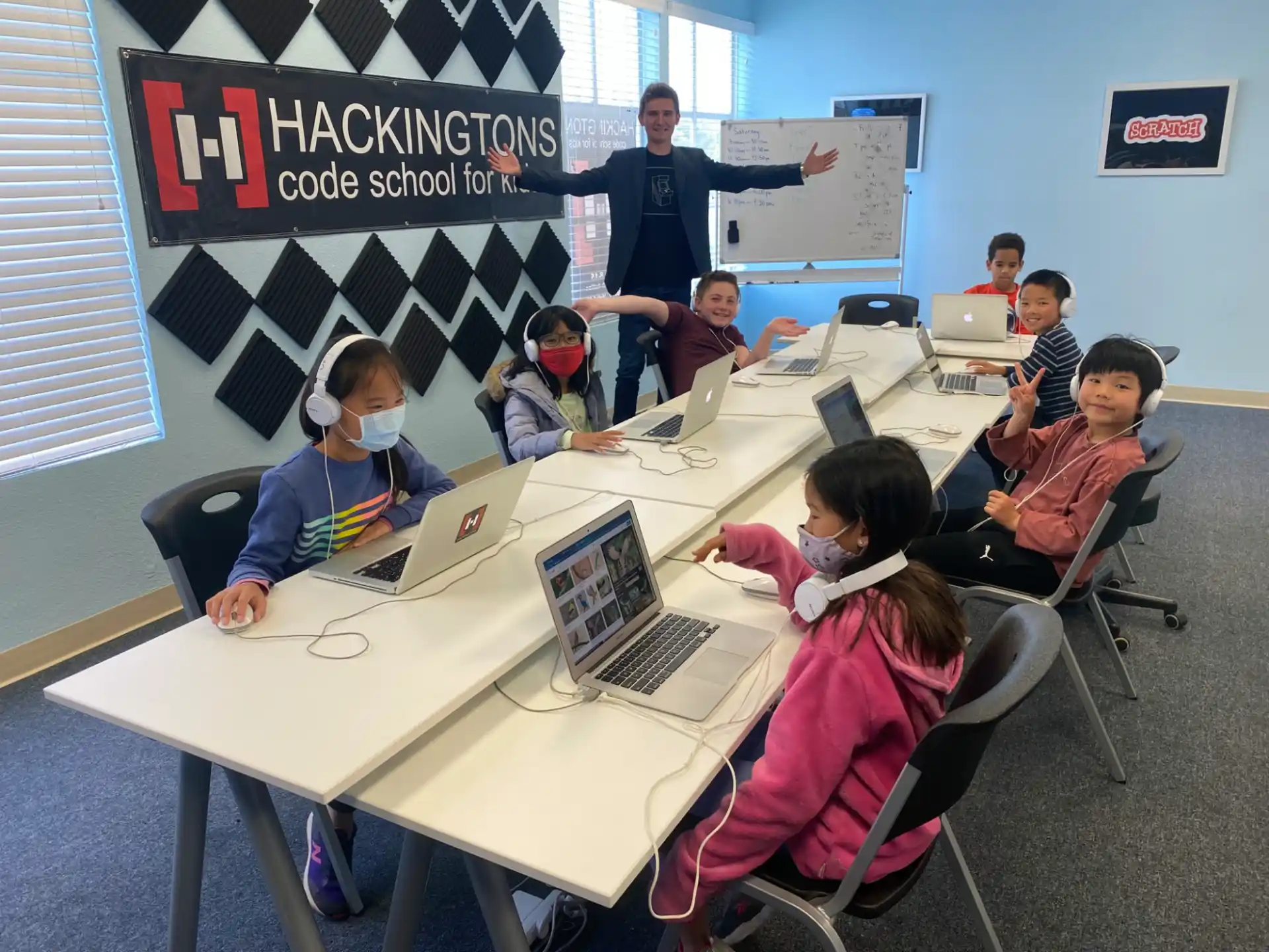 a group of people sitting at a table with laptops