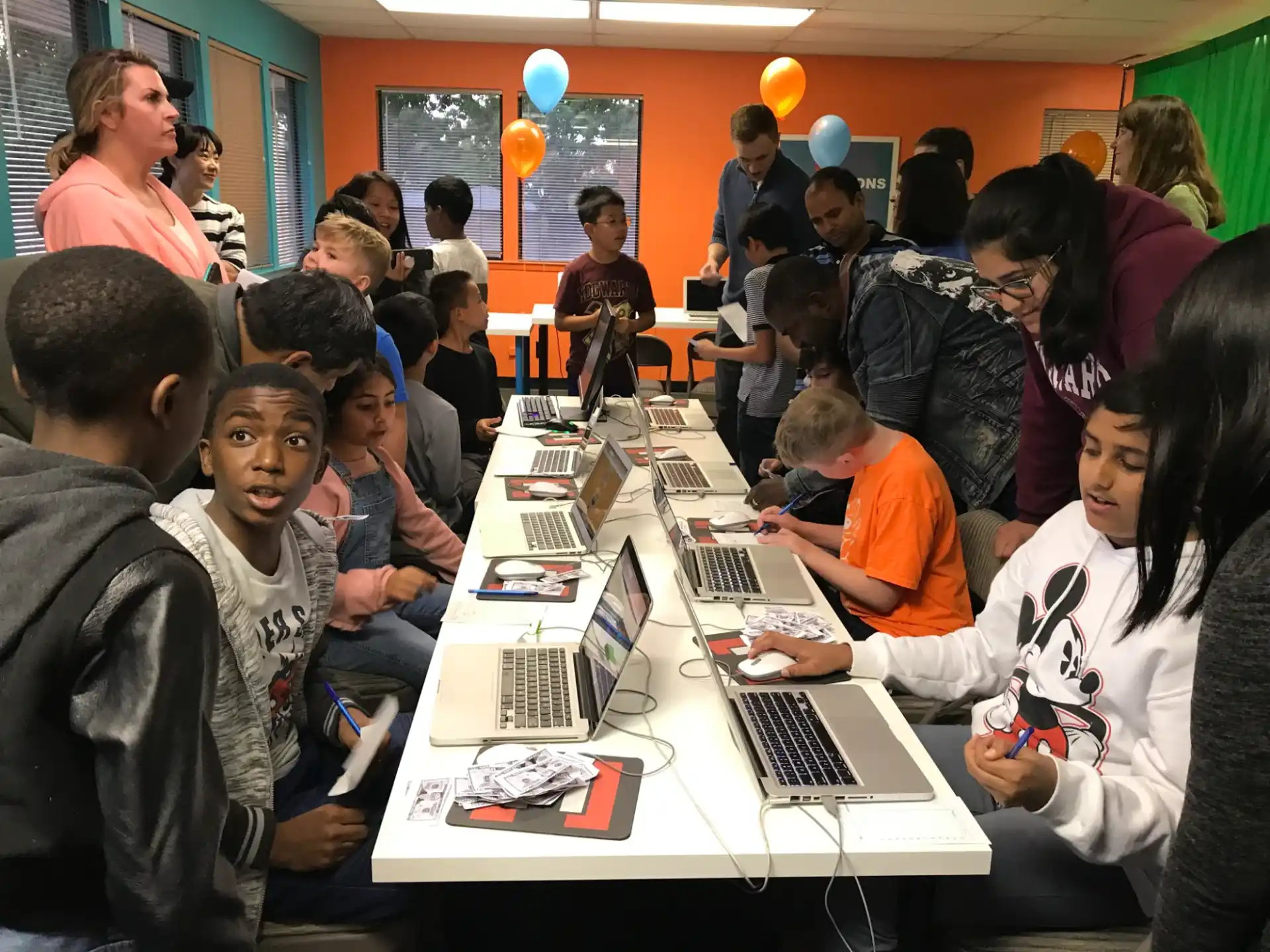 a group of people sitting around a table with laptops