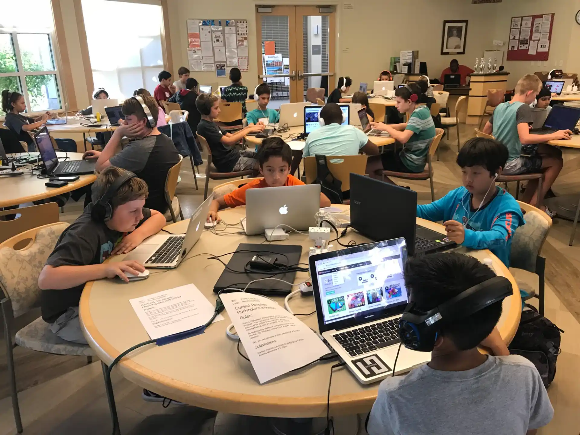 a group of people sitting at a table with laptops