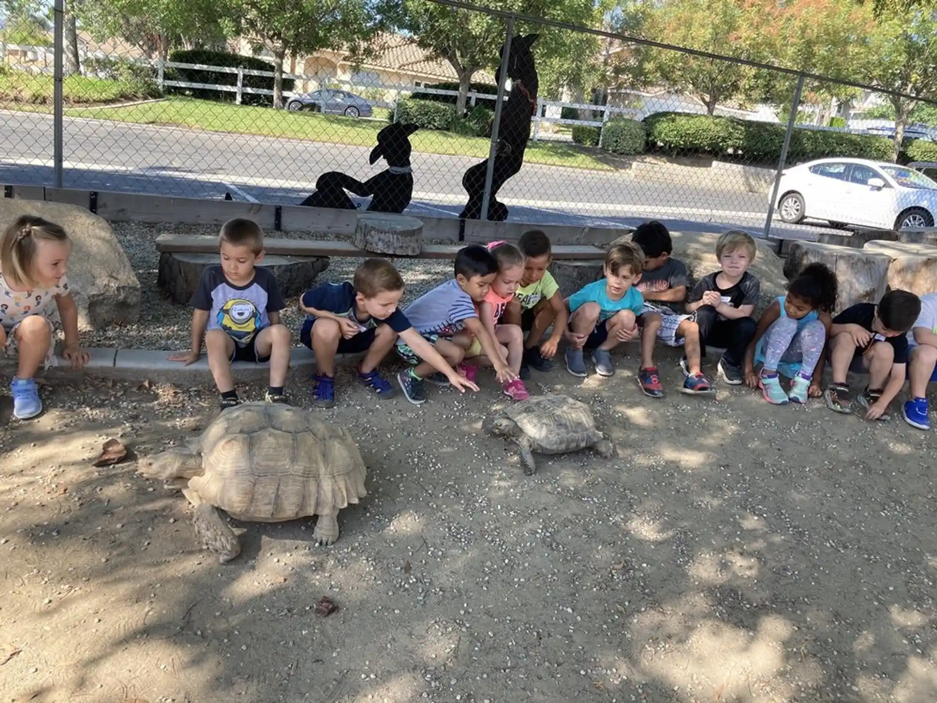 a group of children sitting on the ground next to a statue