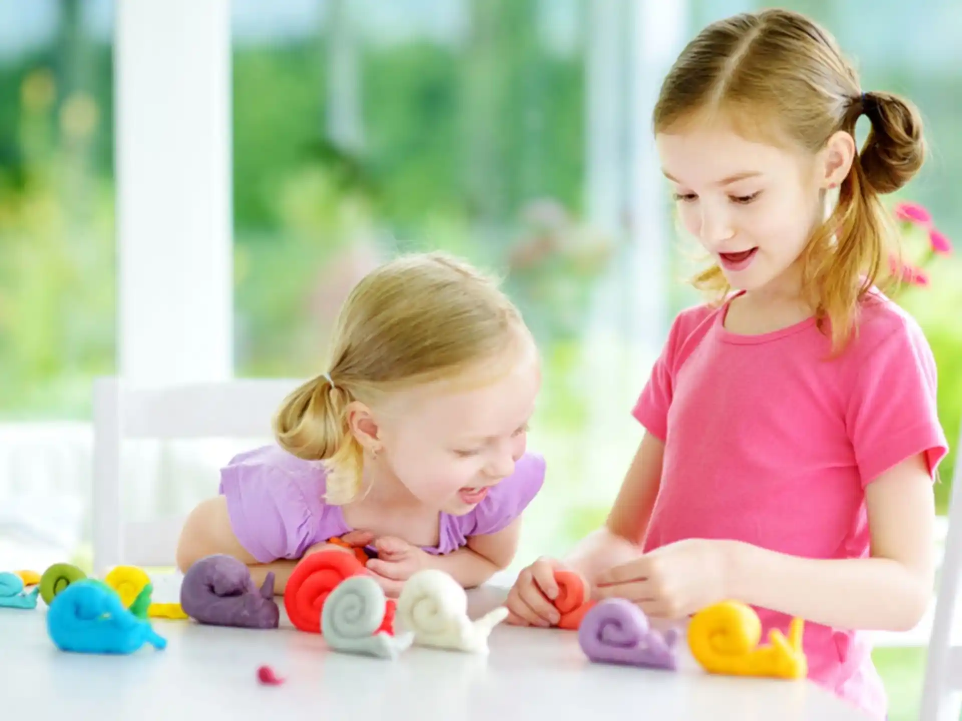 a couple of young girls playing with toys on a table