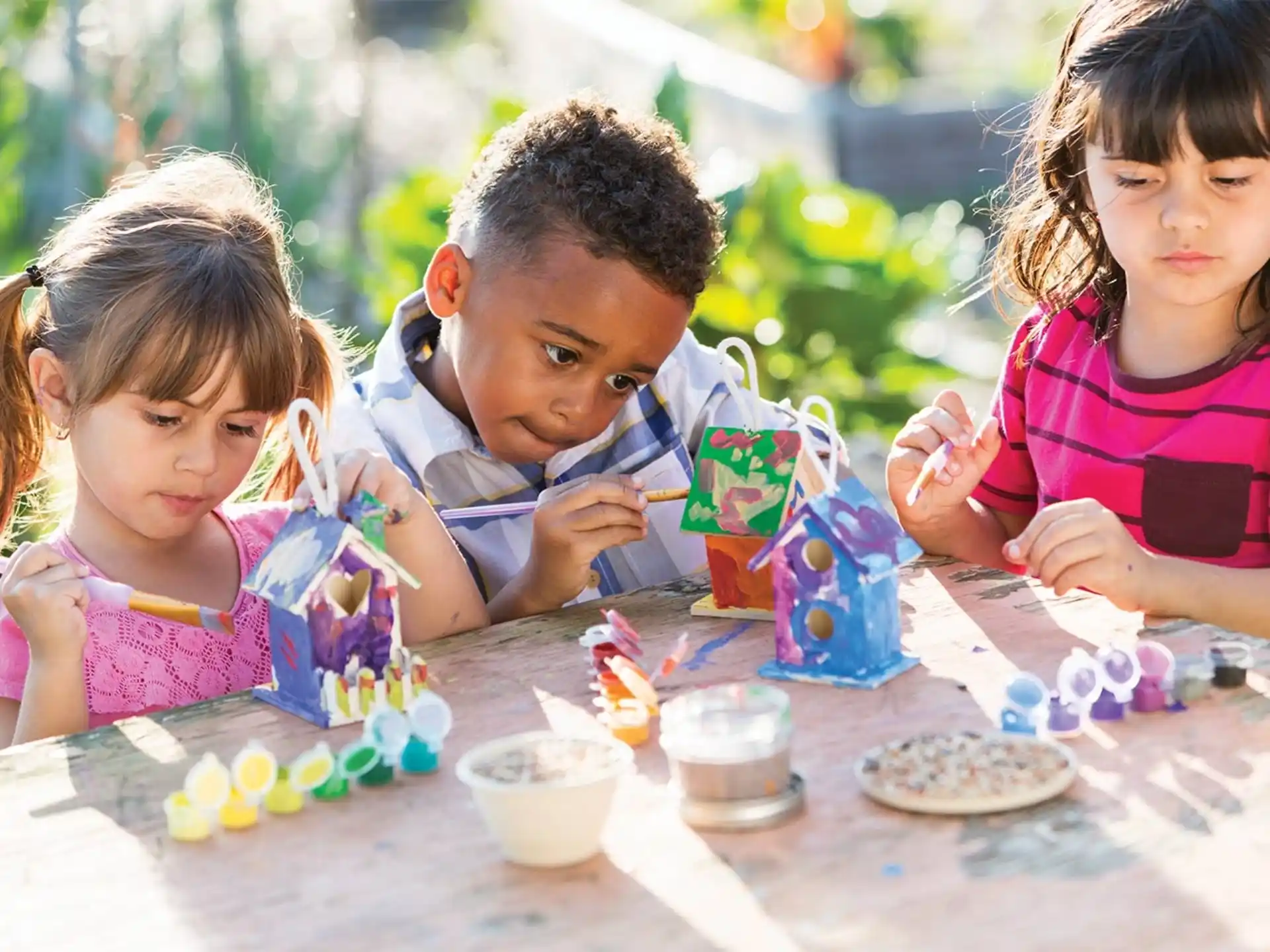 a group of children sitting at a table with food