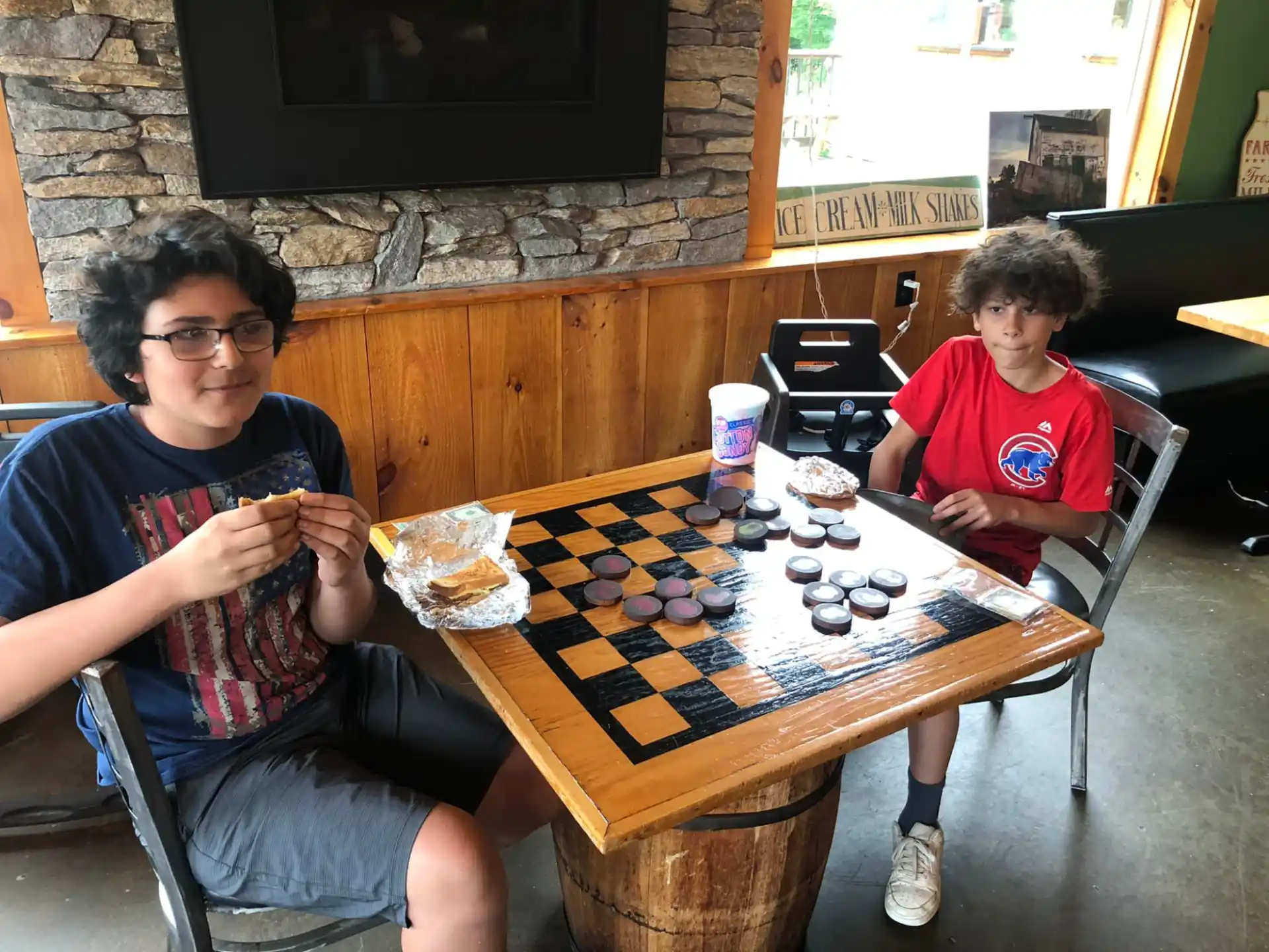 a person and a boy sitting at a table with a board game