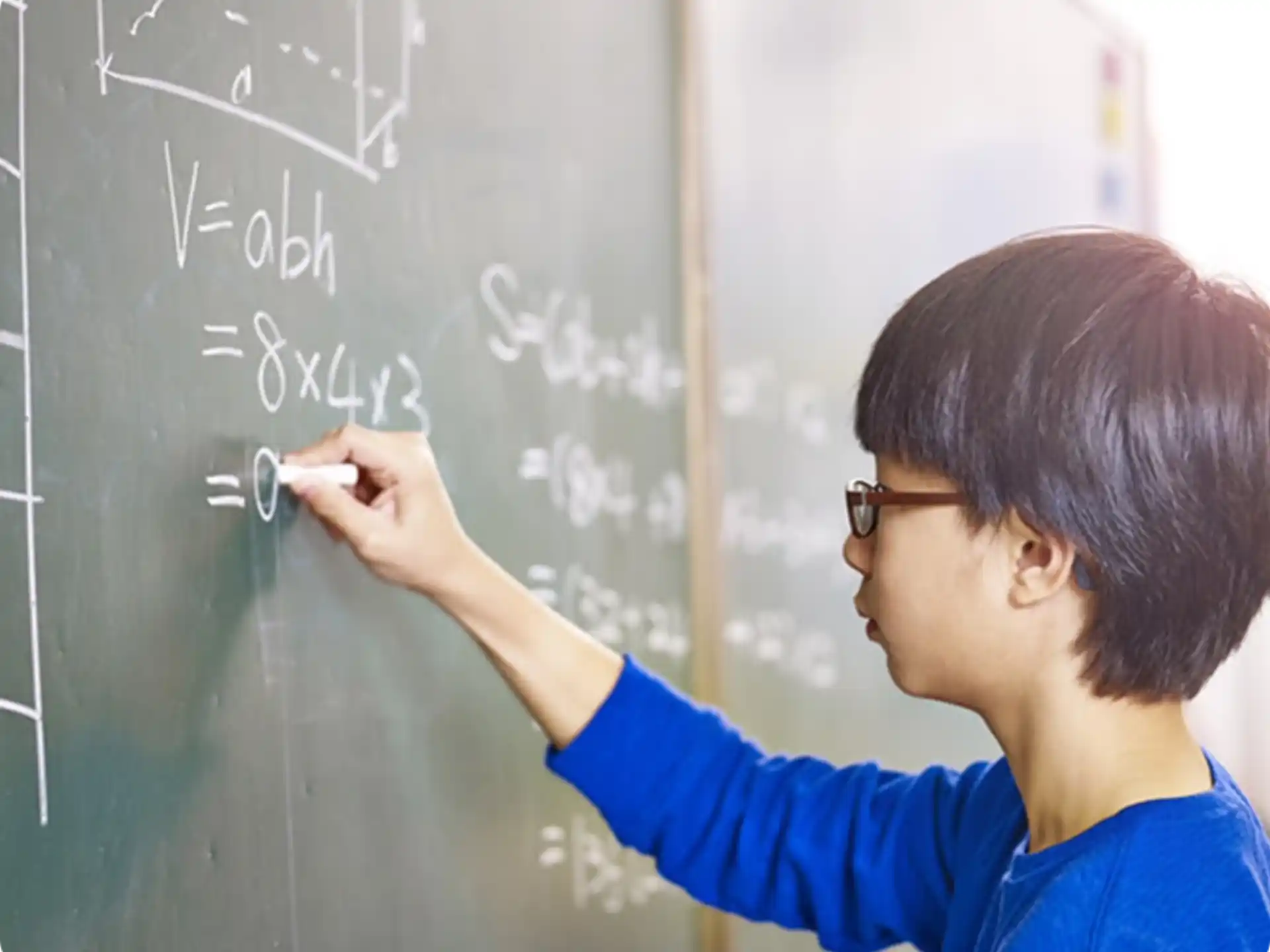 a young man writing on a blackboard