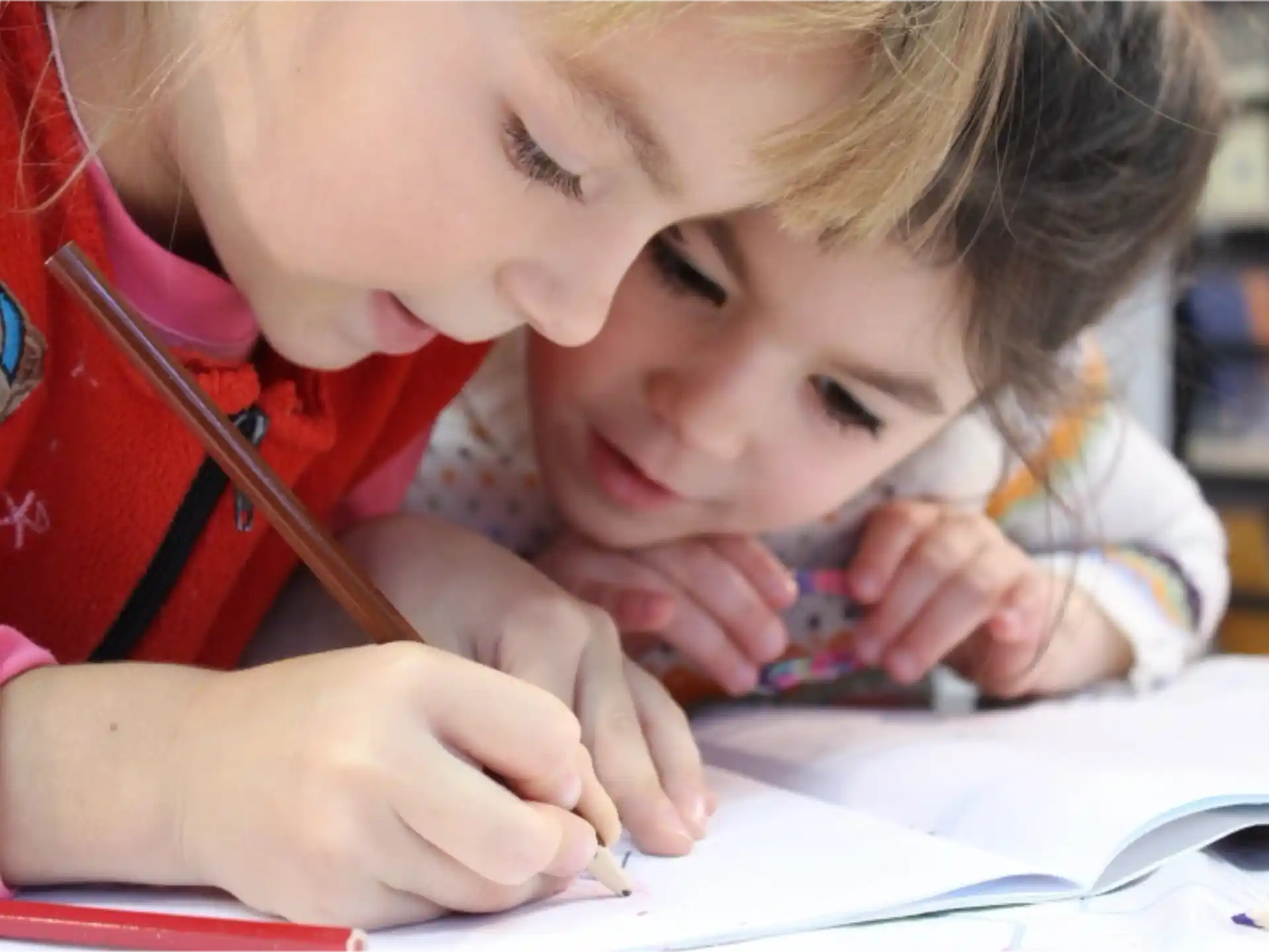 a young girl and a young boy looking at a book