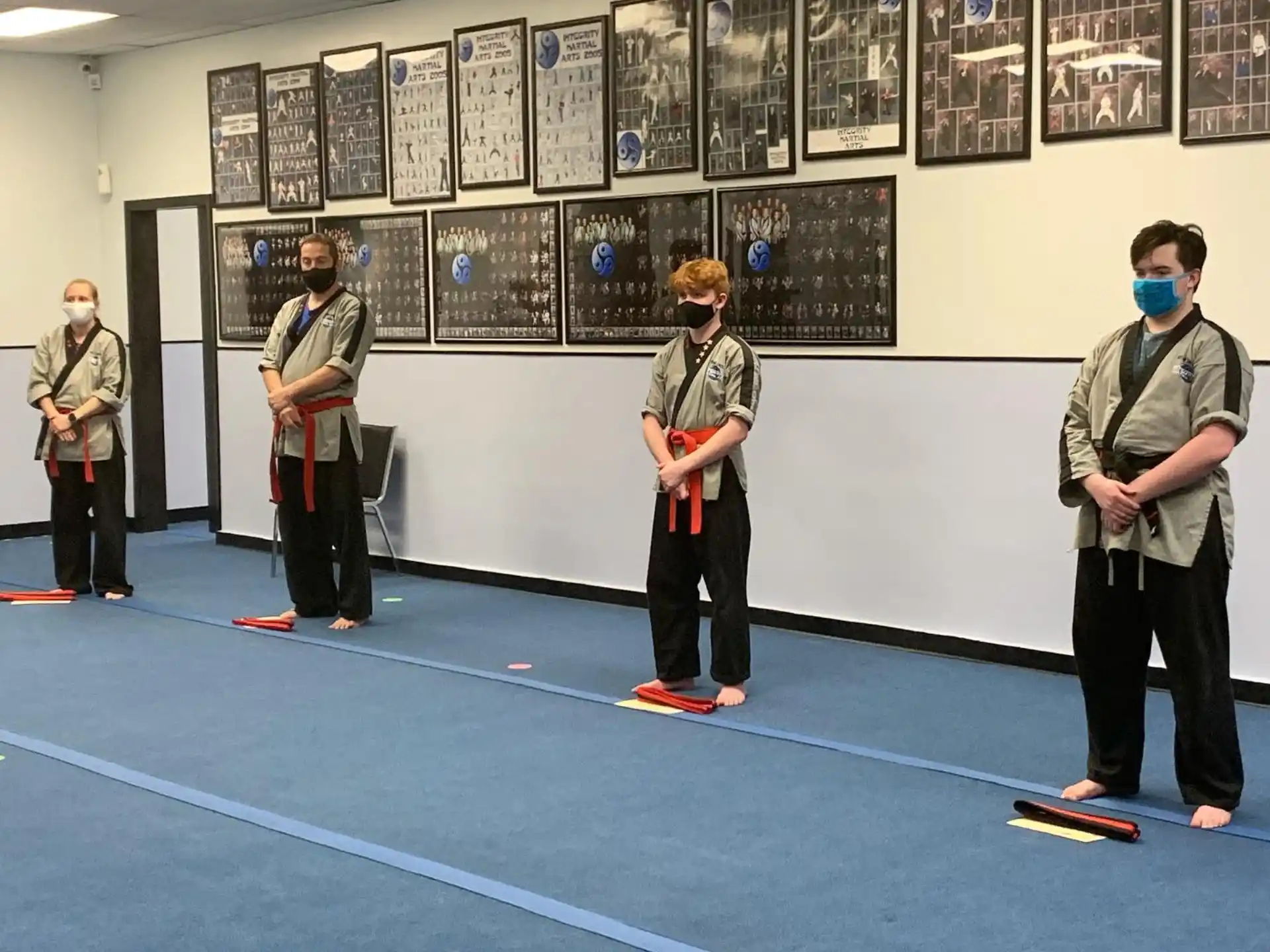 a group of people standing on a blue mat in front of a wall of pictures