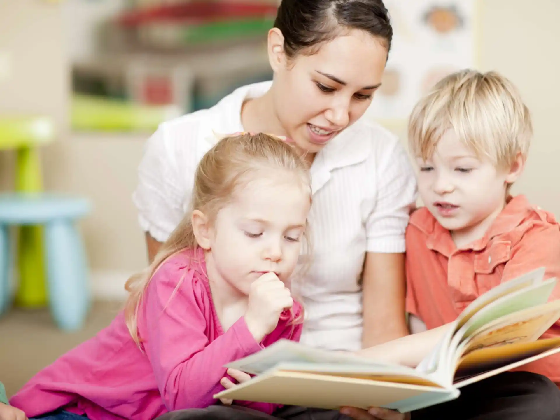 a person reading a book to a few children
