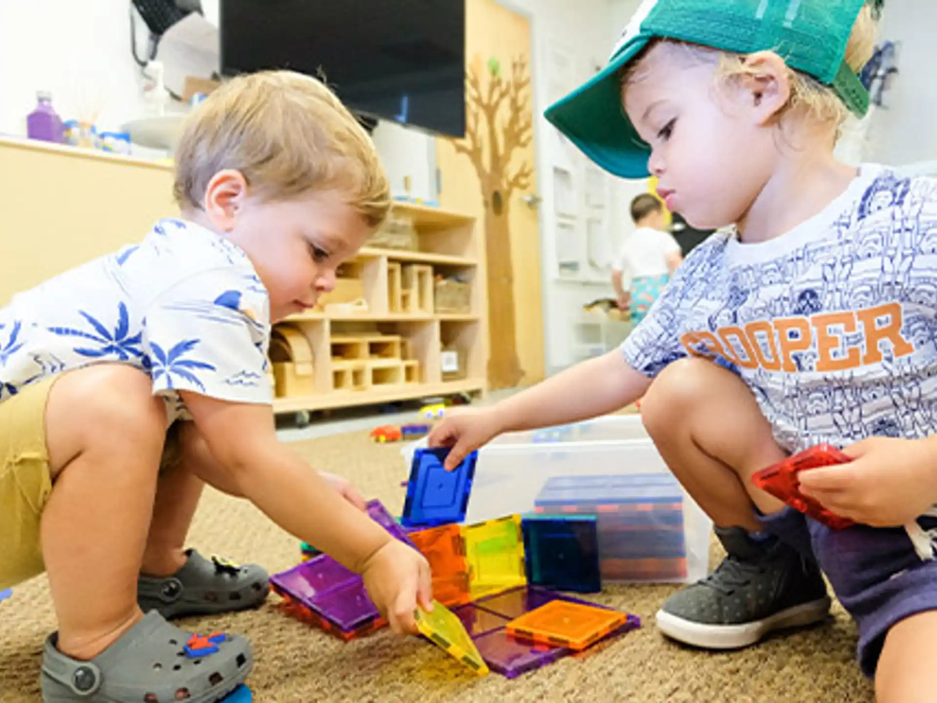 a couple of young boys playing with toys on the floor