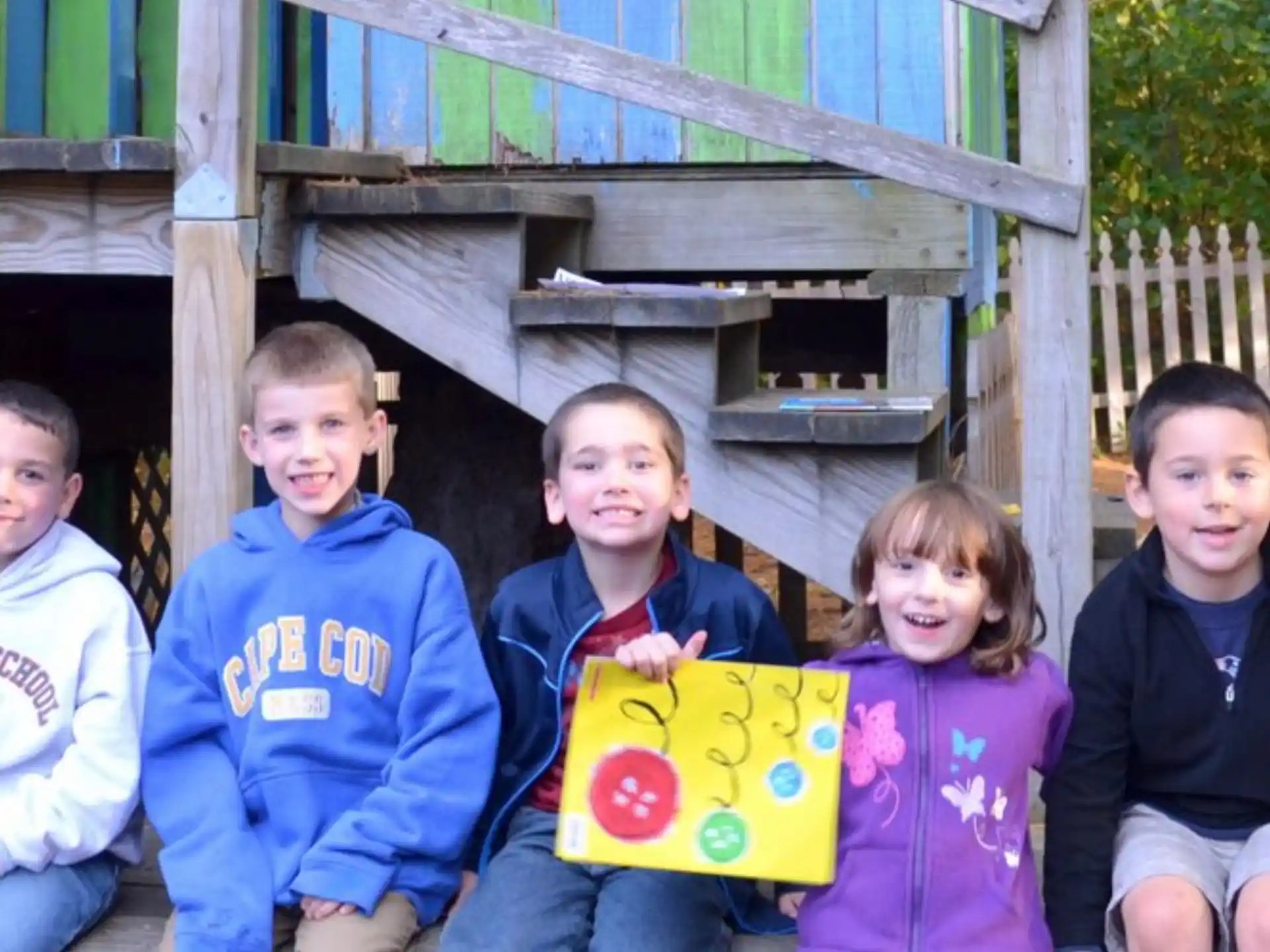 a group of children sitting on a bench posing for the camera