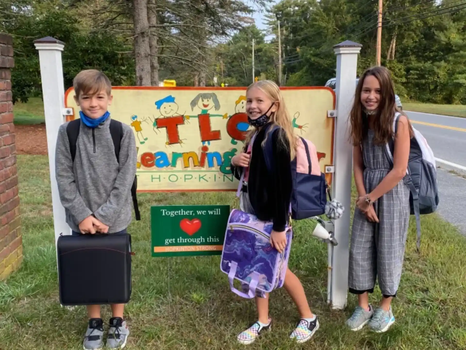 a group of girls standing next to a sign