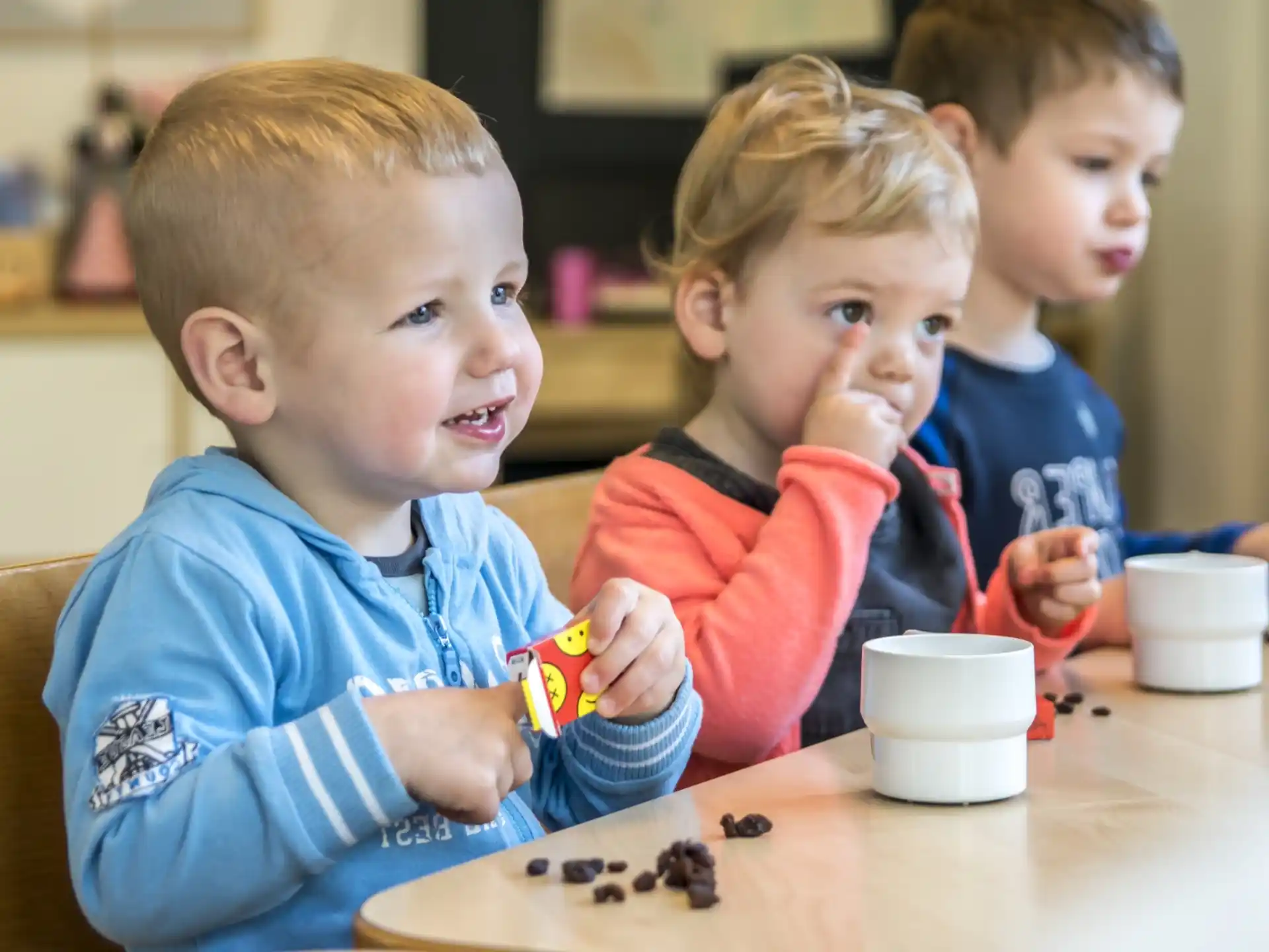 a group of children sitting at a table playing with toys