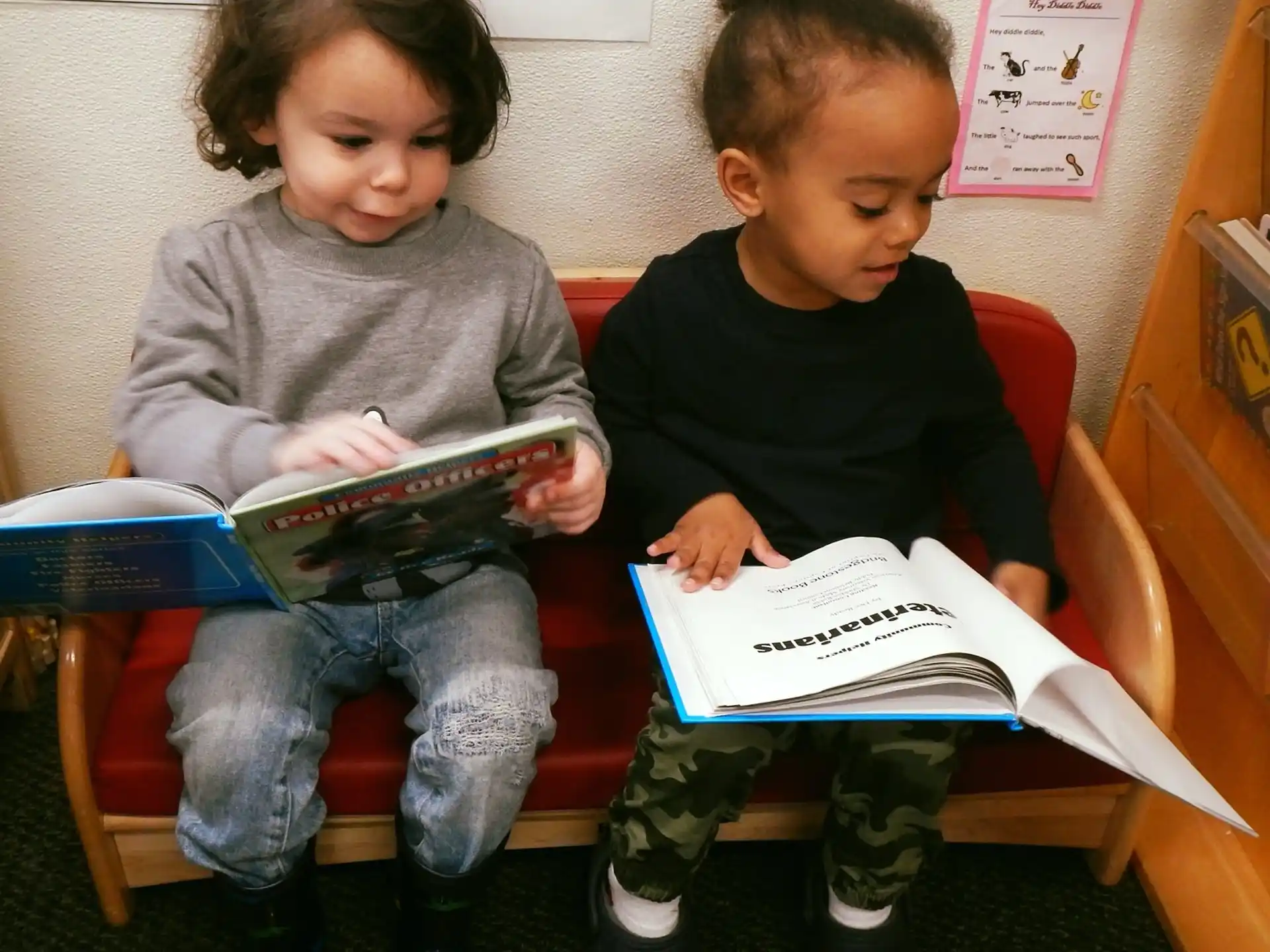 a couple of children sitting on a bench reading books