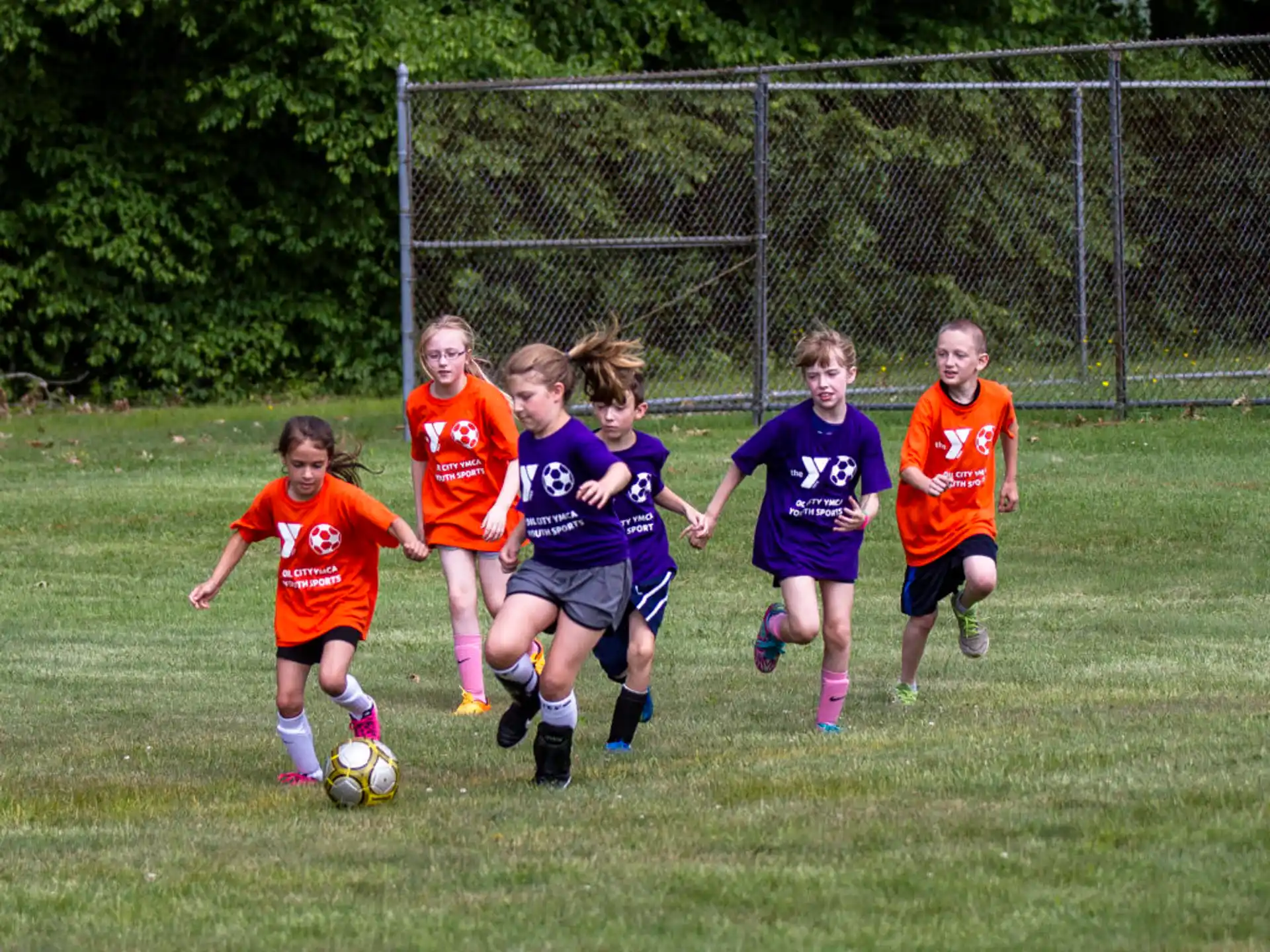 a group of kids compete over a football ball