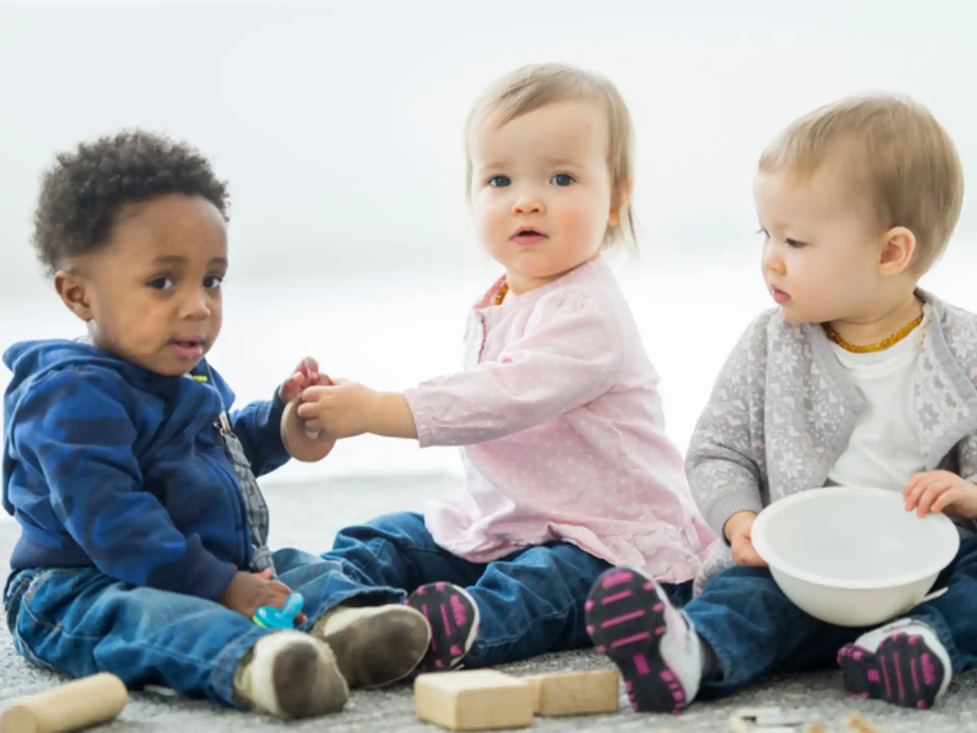 a group of children sitting on the floor eating from a bowl