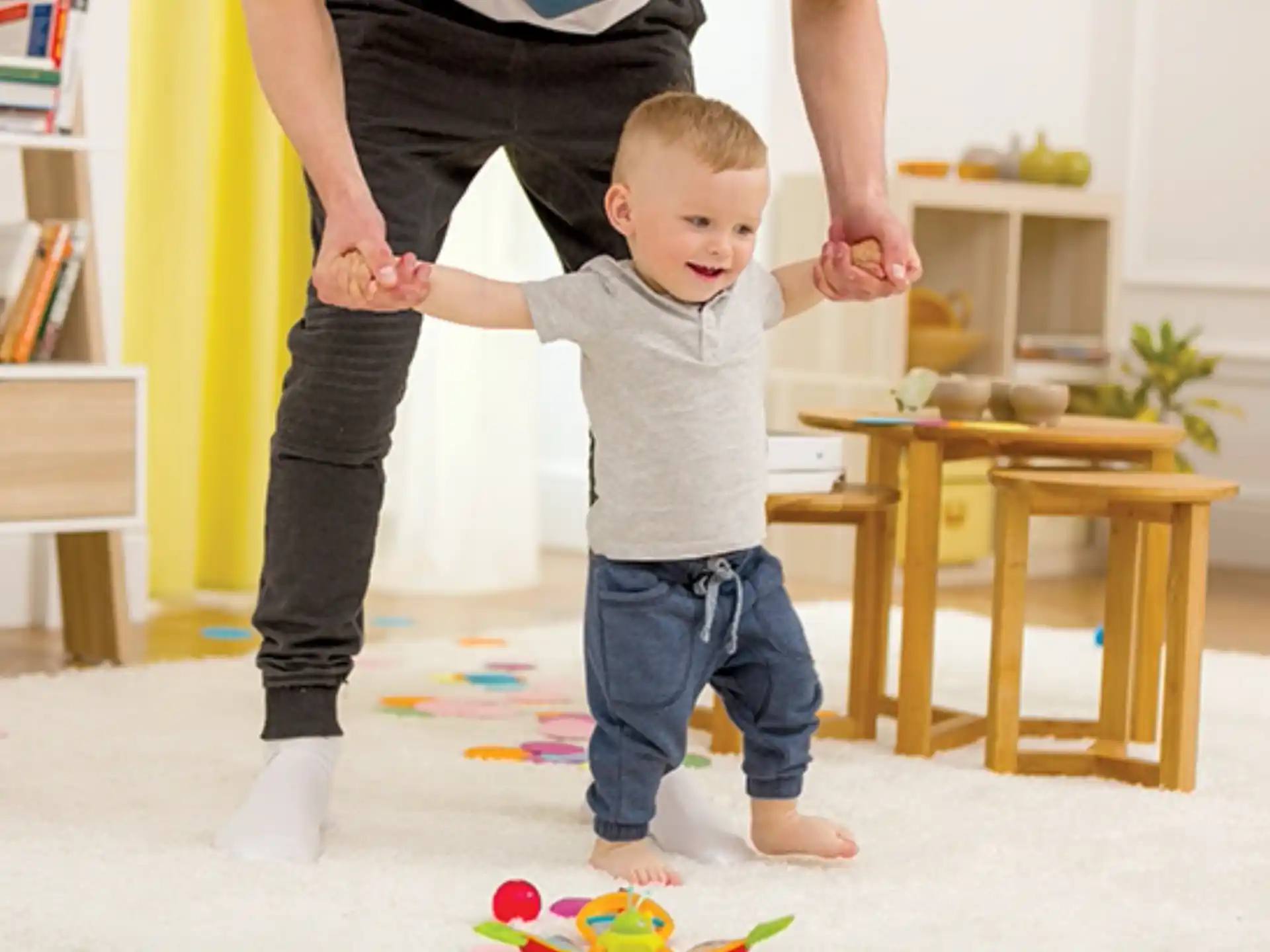 a baby standing on a woman's legs