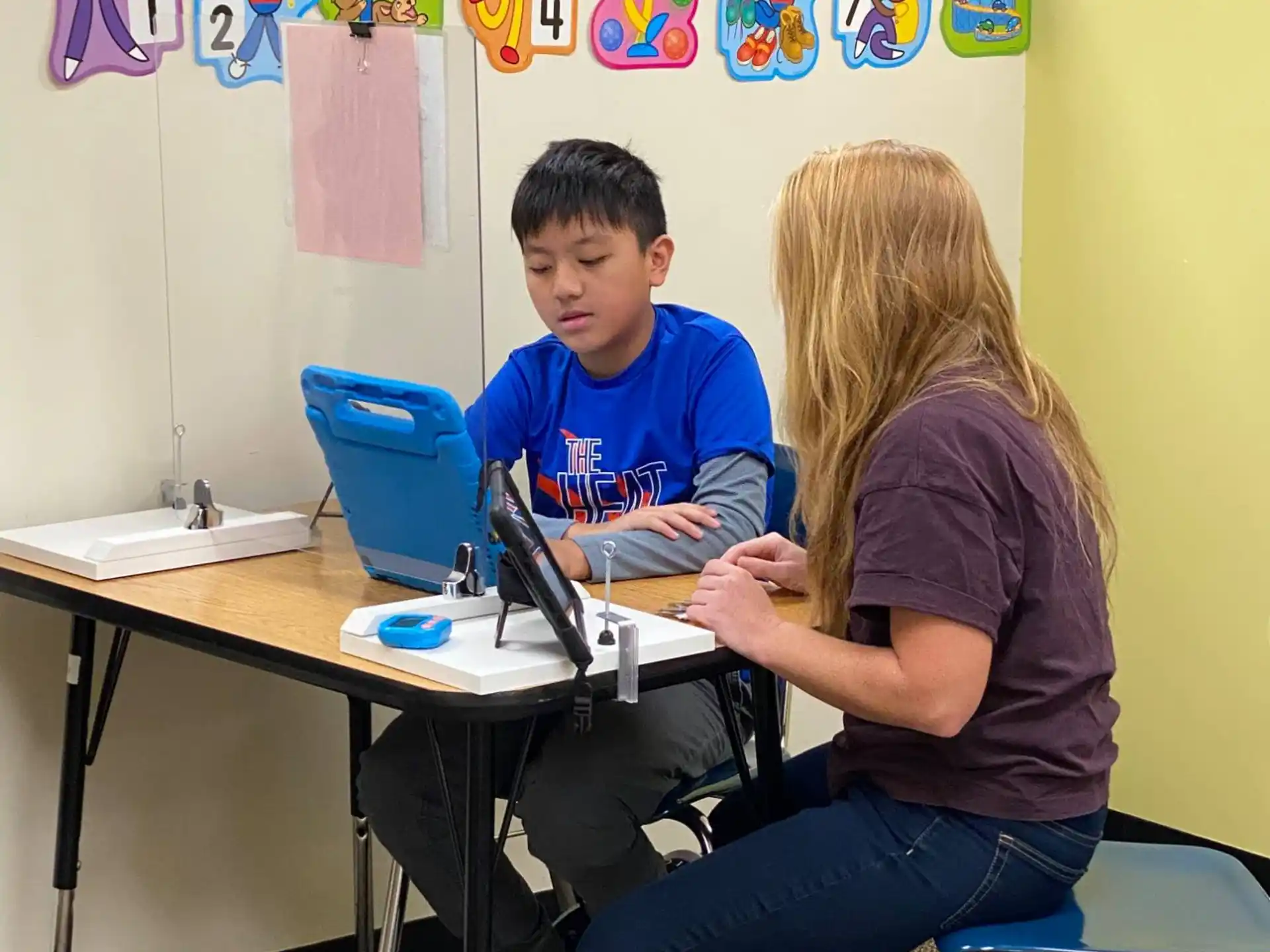 a boy and girl sitting at a table with a laptop