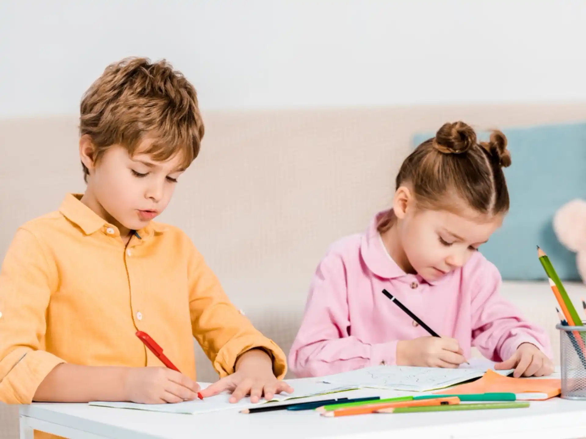 a couple of children sitting at a table looking at a book