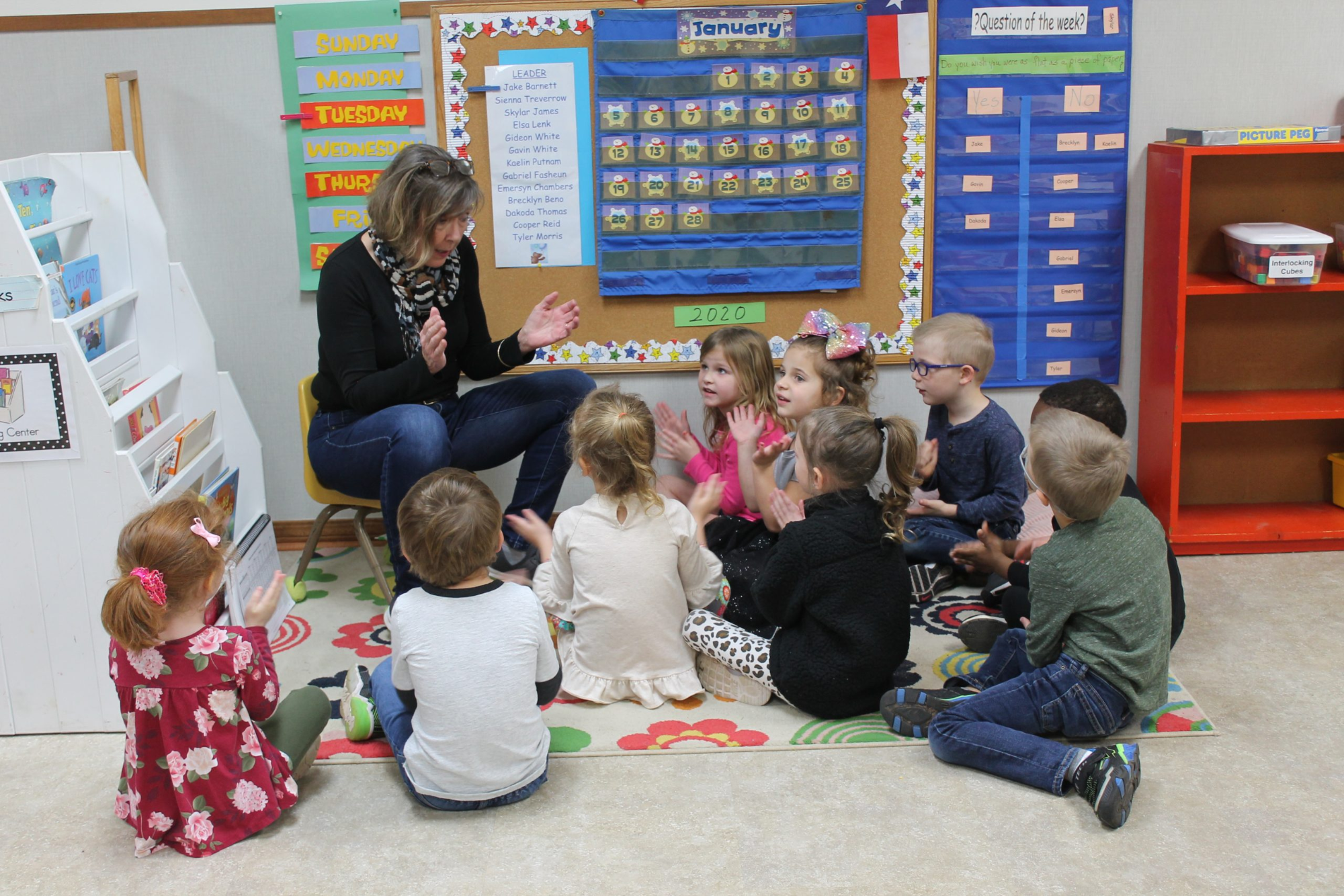 a person and several children sitting in a classroom
