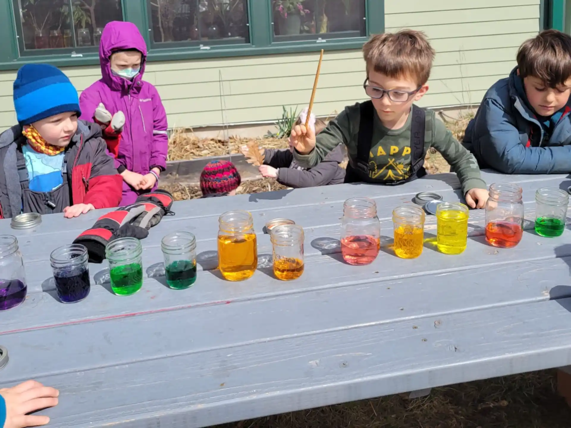 a group of kids sitting at a table with cups of liquid