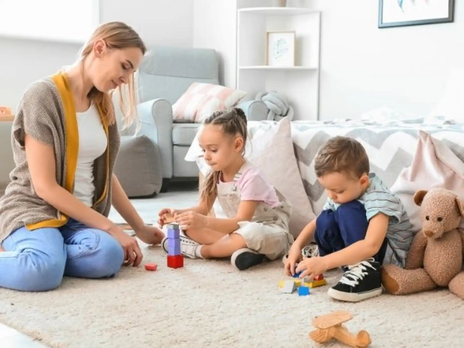 a person and two children playing with toys on the floor