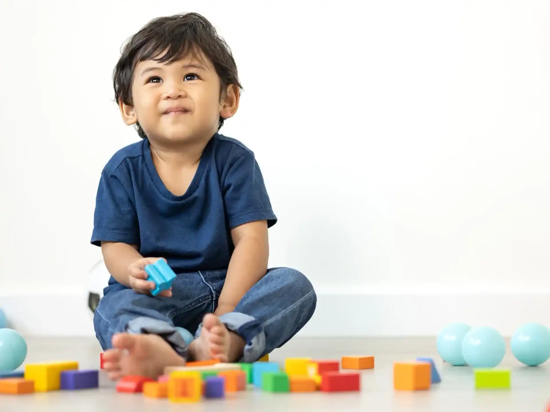 a boy sitting on the floor with colorful blocks