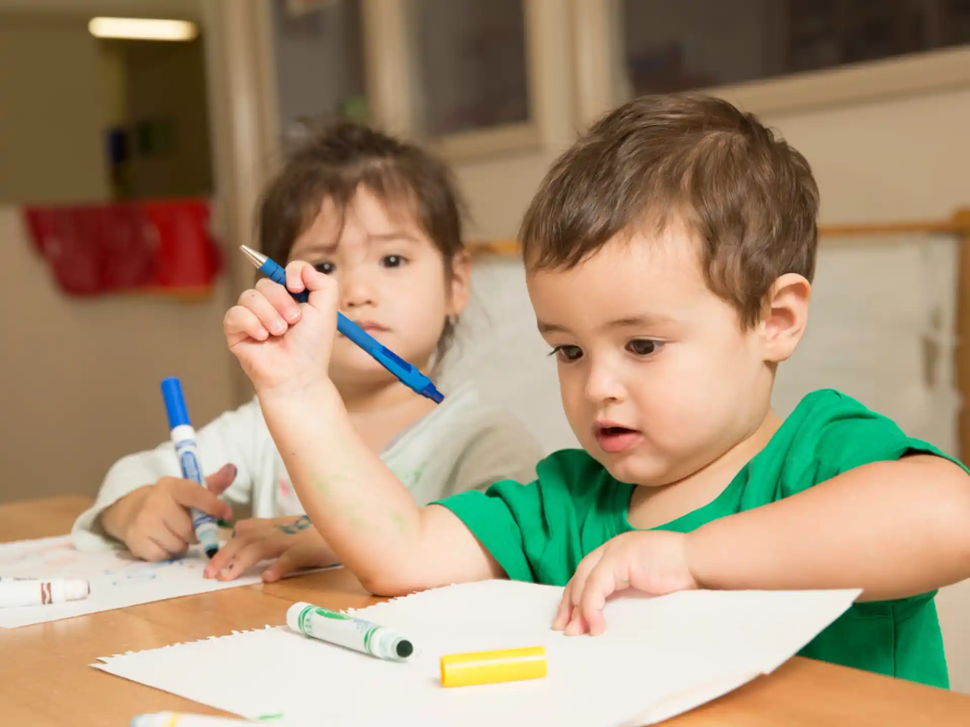 a couple of boys sit at a table with toothbrushes